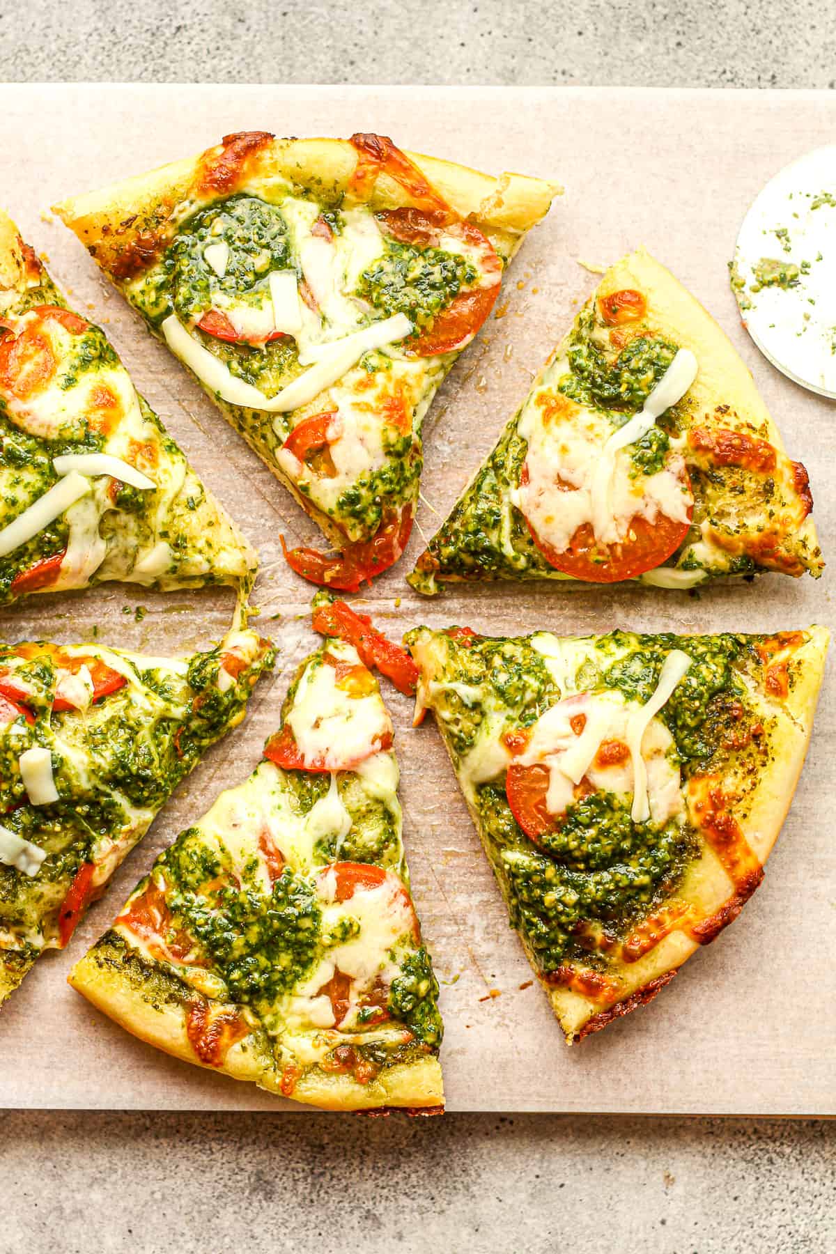 Six slices of pesto pizza with tomatoes and fresh mozzarella cheese.
