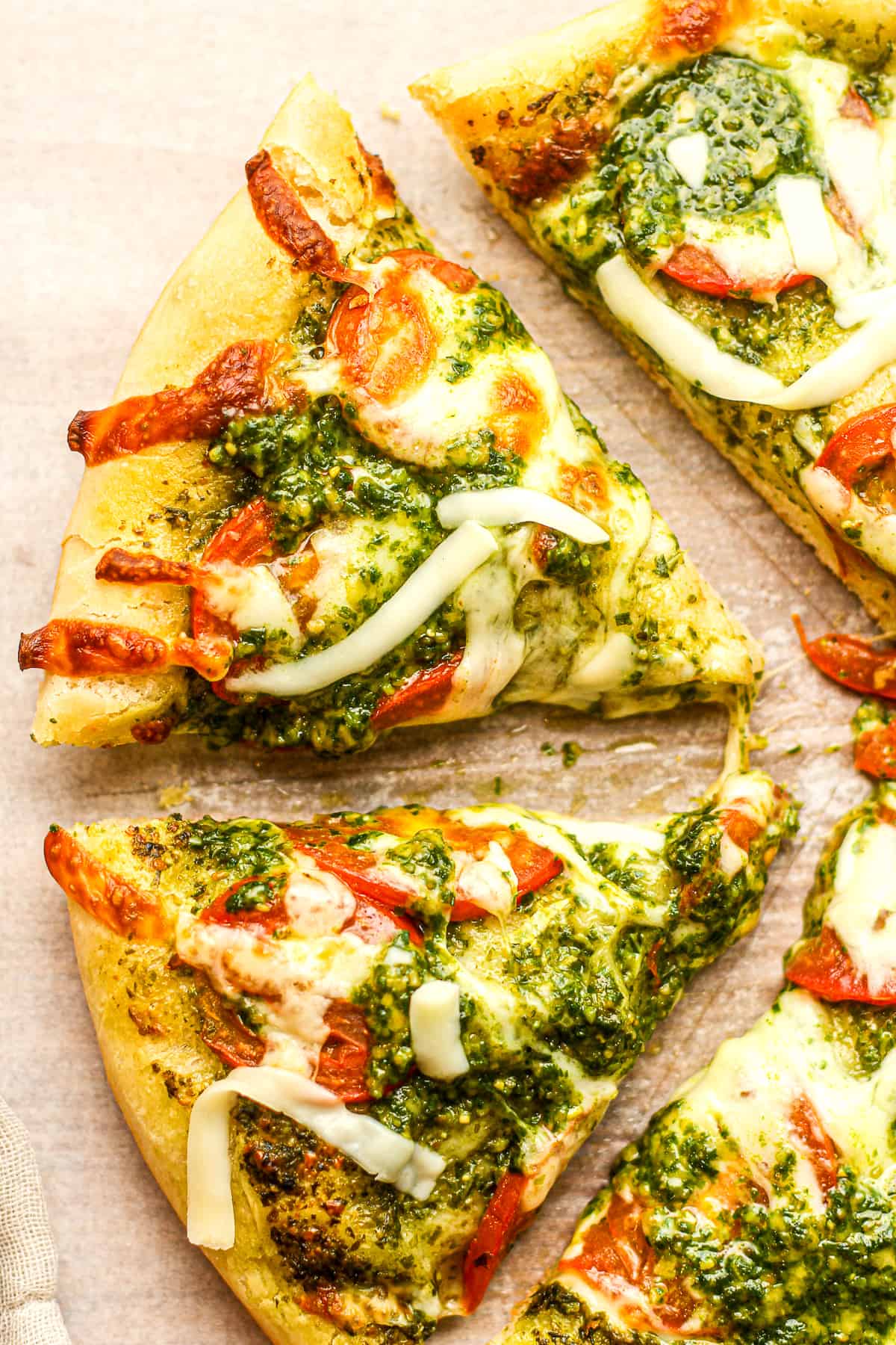 Closeup on some sliced pesto pizza with tomatoes.