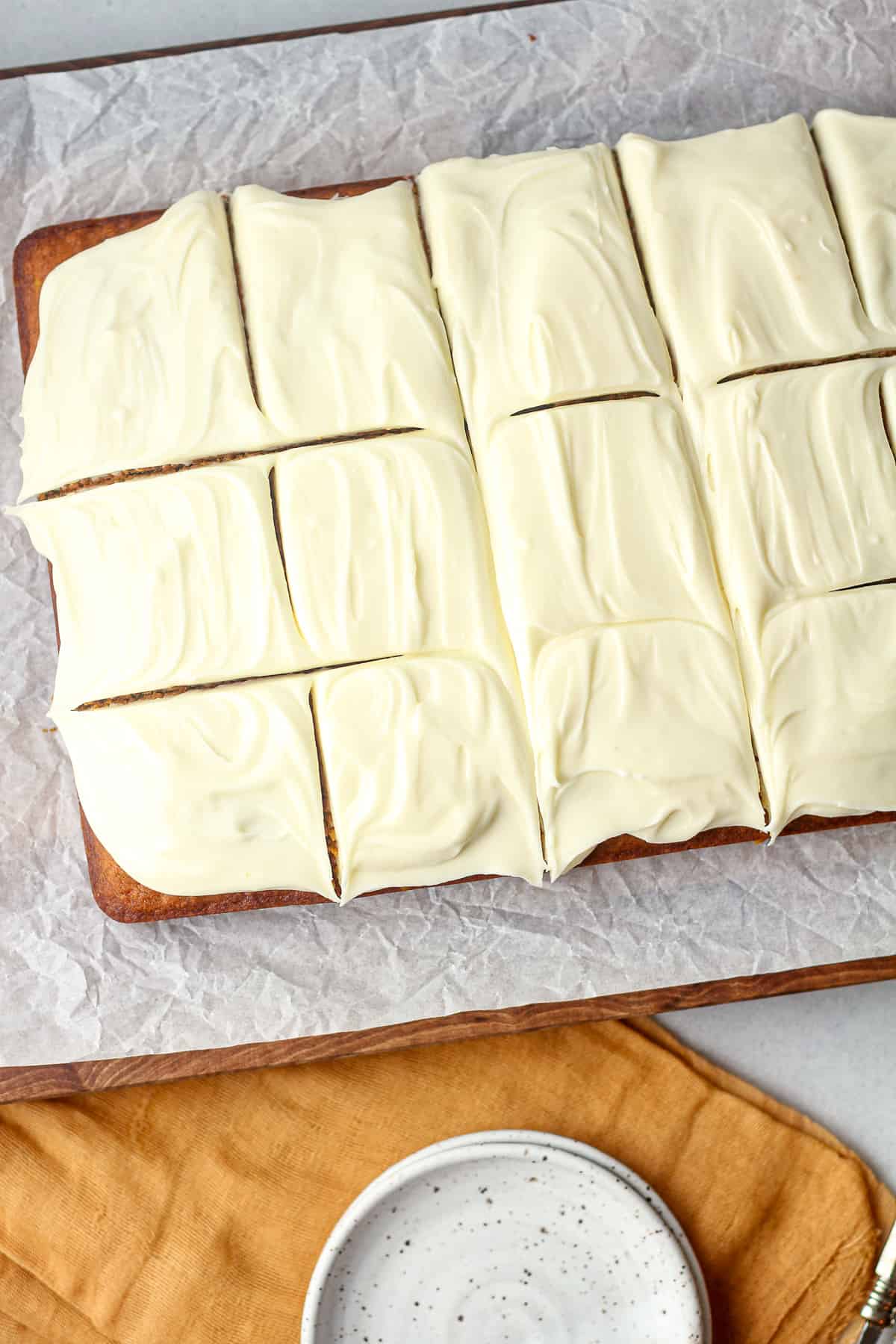Overhead view of a sliced pumpkin cake with cream cheese frosting.