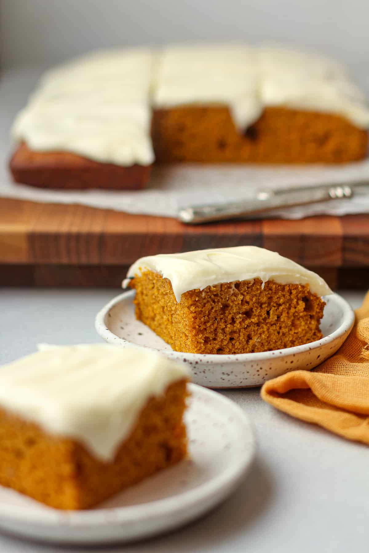 Side view of two slices of frosted pumpkin cake.