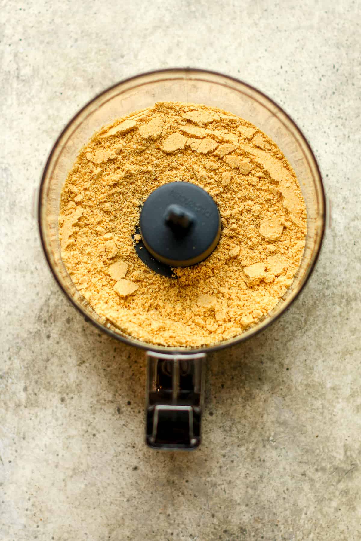 A mini food processor with blended graham crackers.