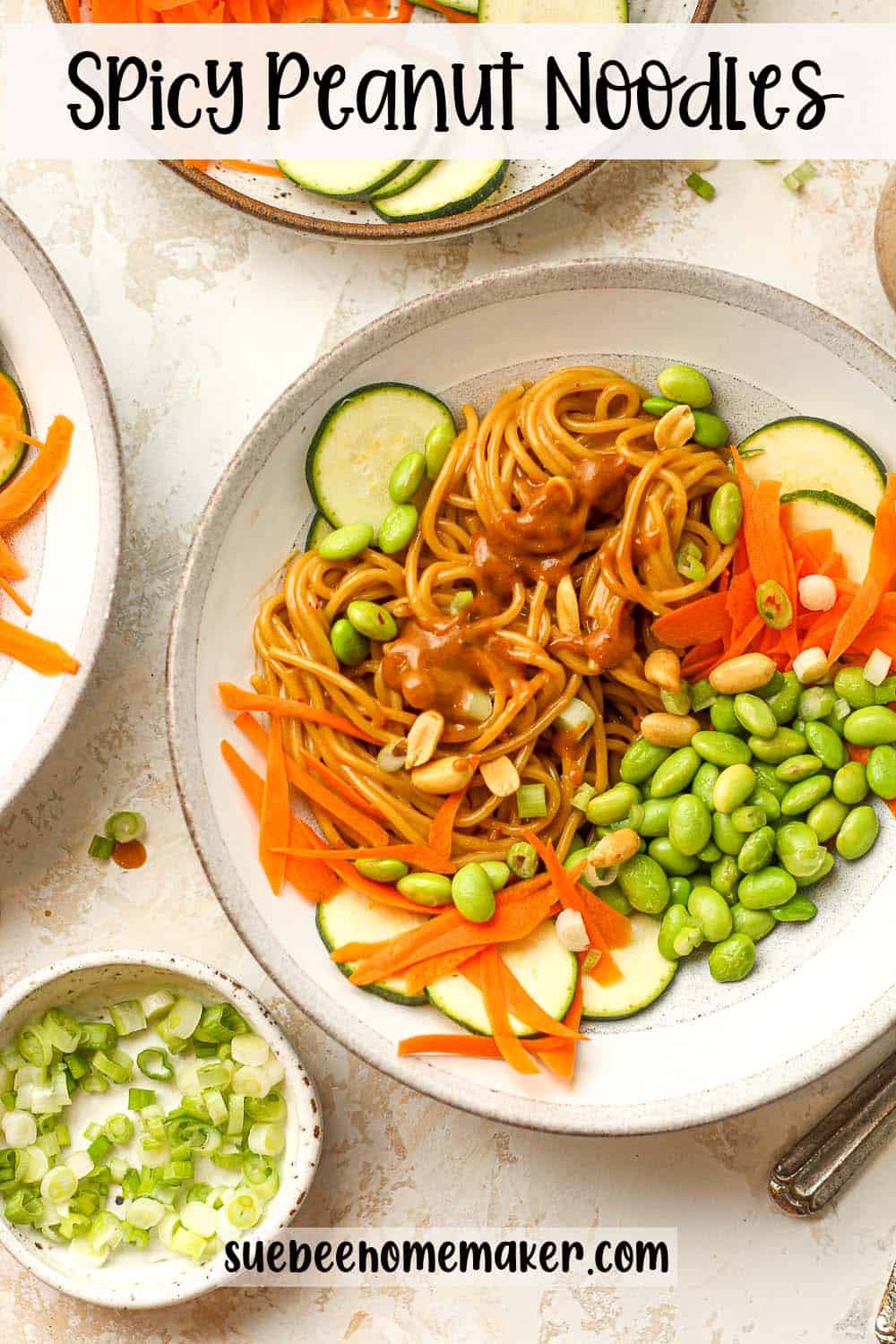 Two bowls of spicy peanut noodles with veggies.