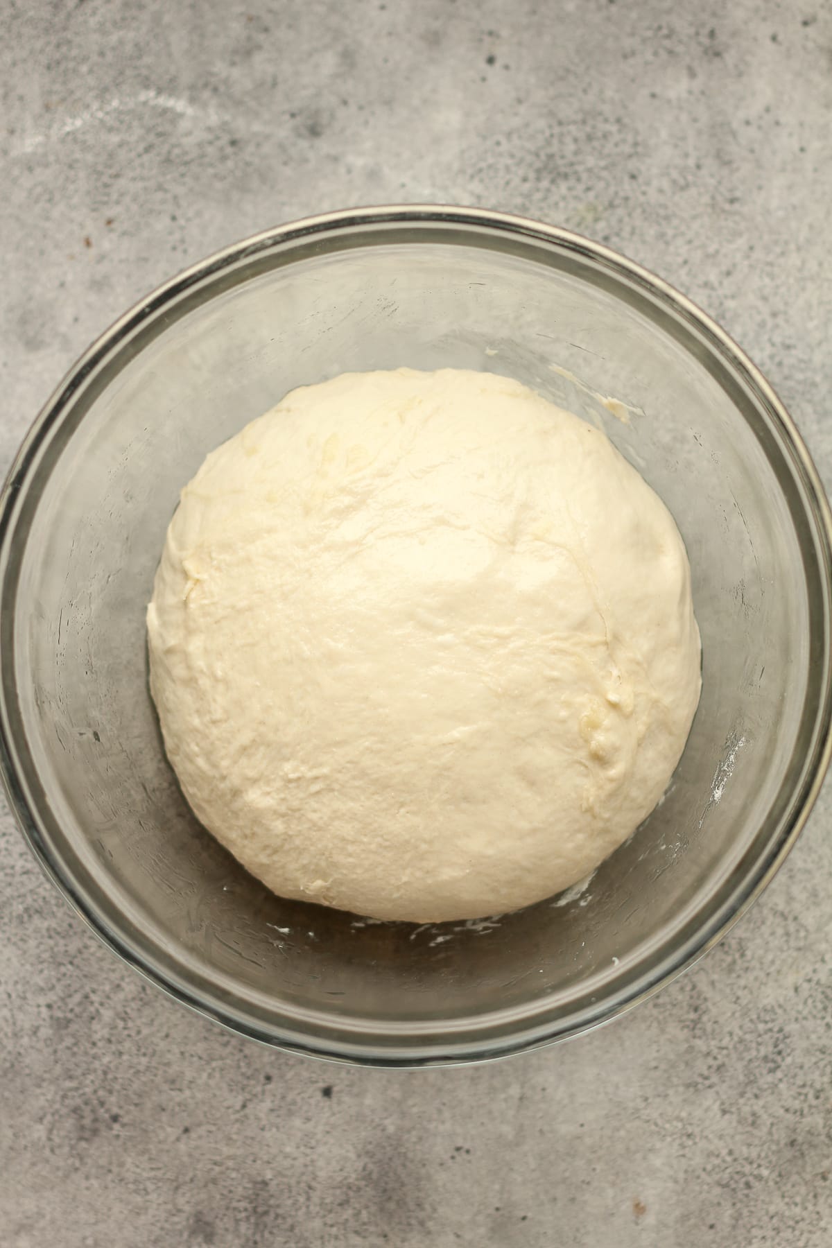 The pizza dough in a glass bowl.