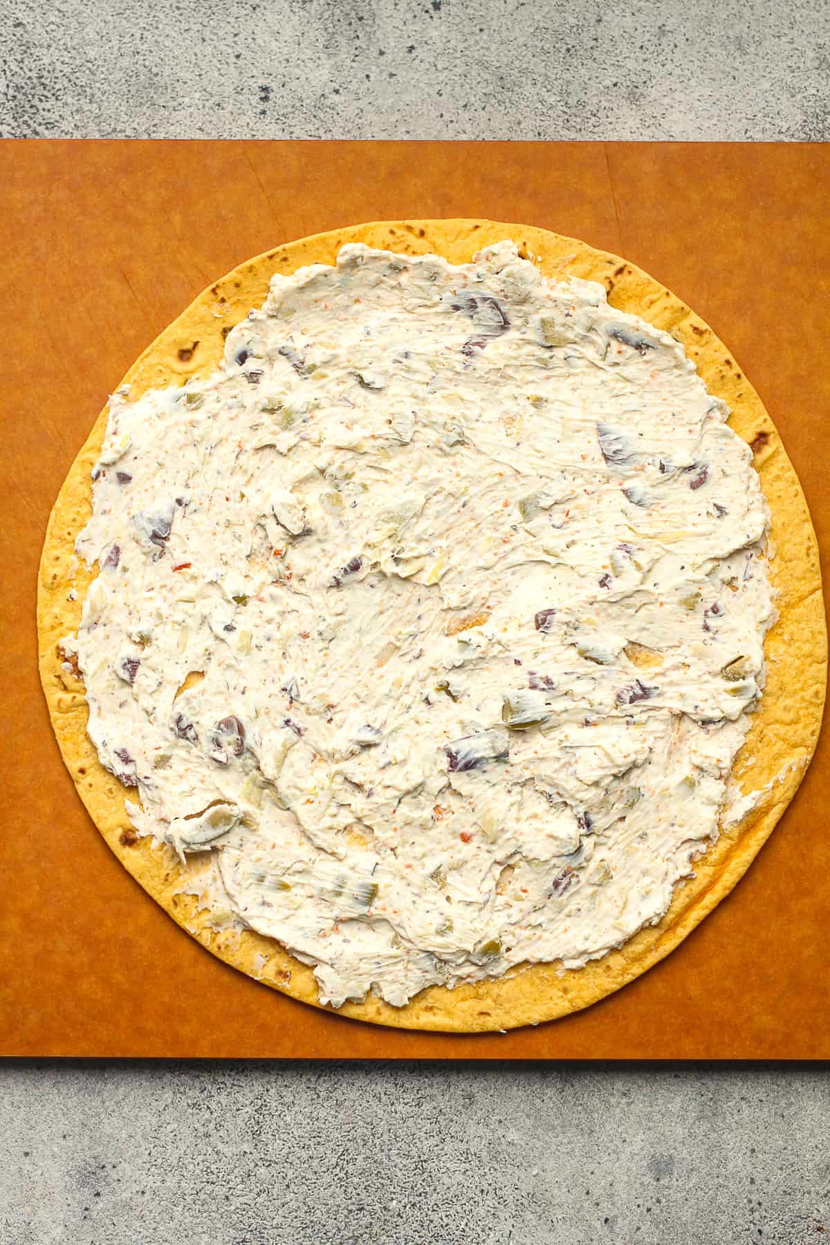 A tortilla with a smear of the cream cheese mixture.