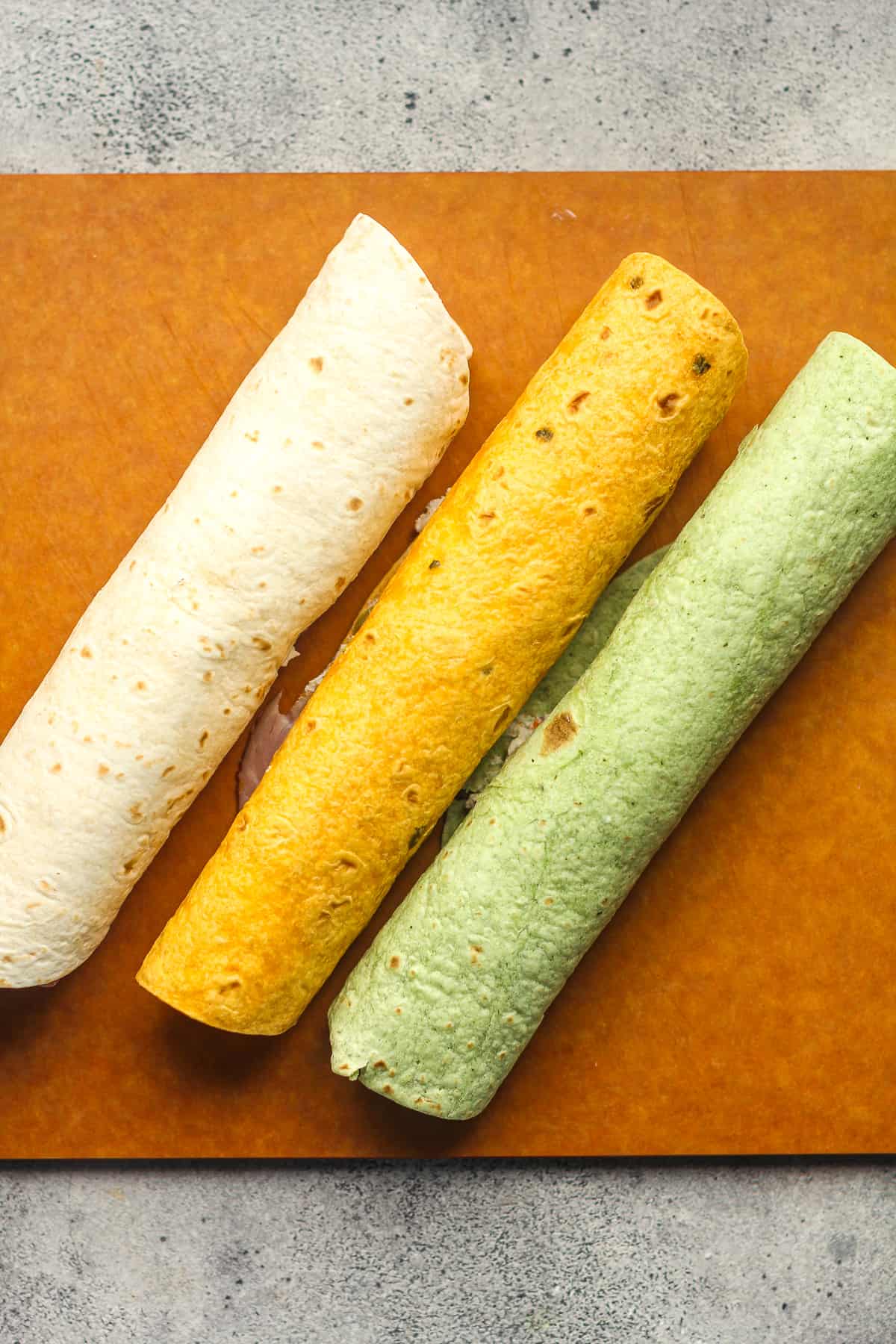 A board with three rolled tortillas.