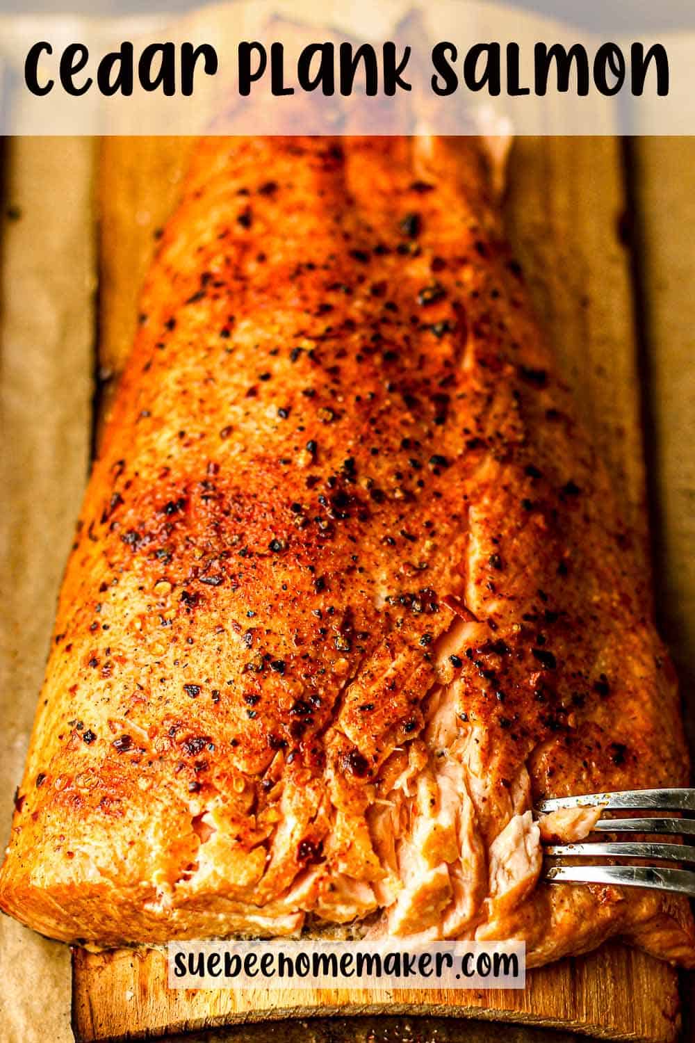 Side view of a large piece of grilled salmon with a fork digging in.
