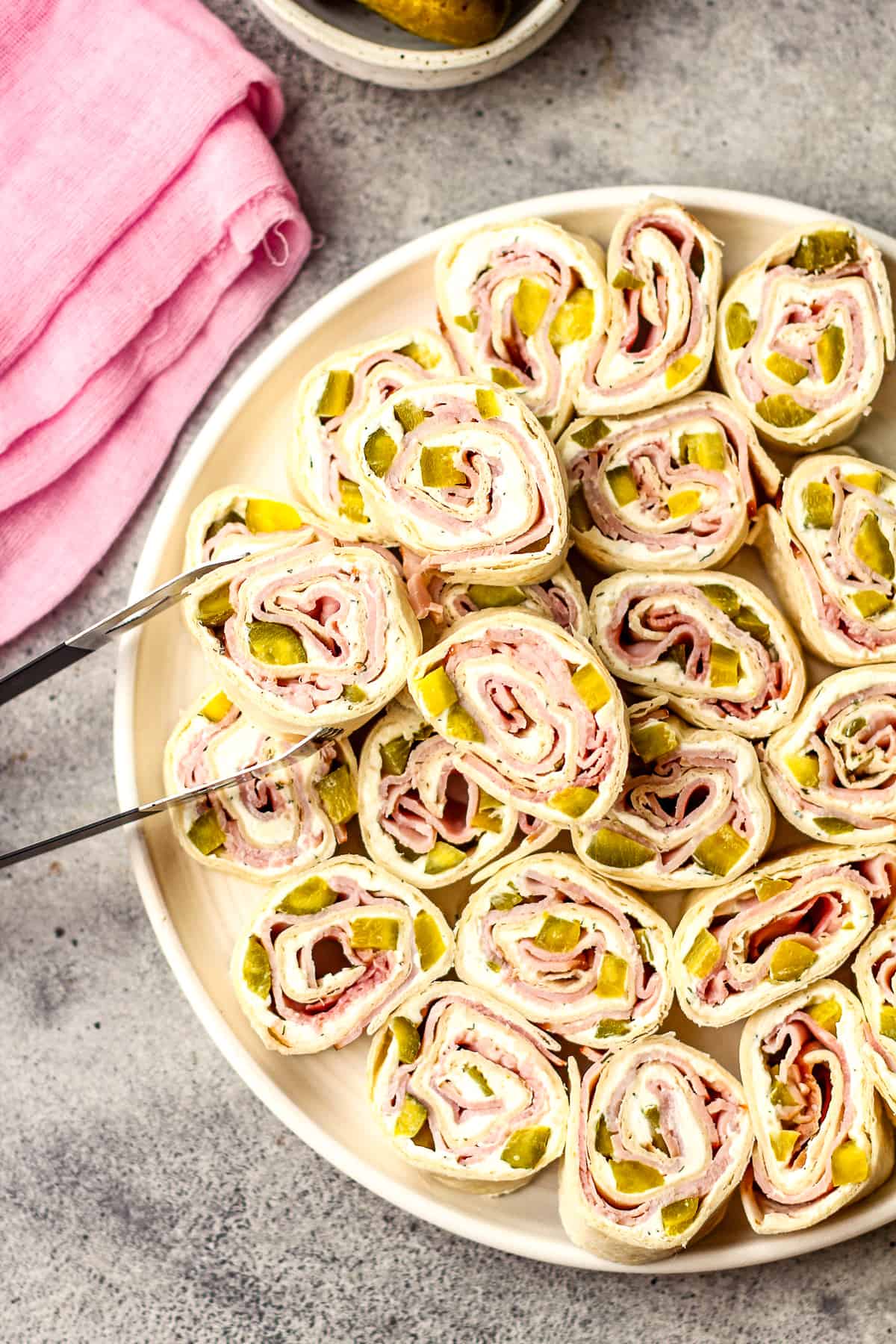 A large plate of dill pickle and ham pinwheels.