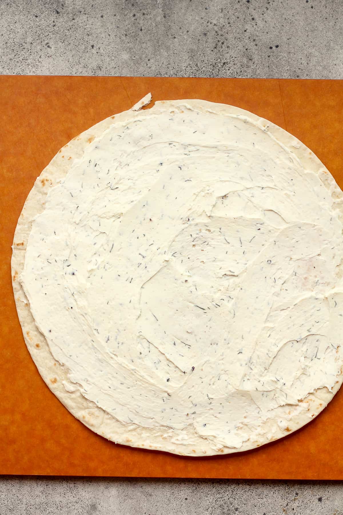 A large tortilla spread with cream cheese and seasonings.