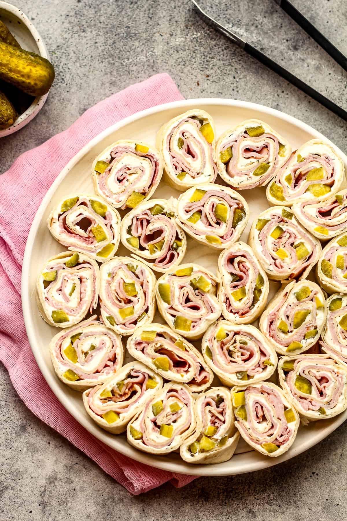A large plate of dill pickle and ham pinwheels.