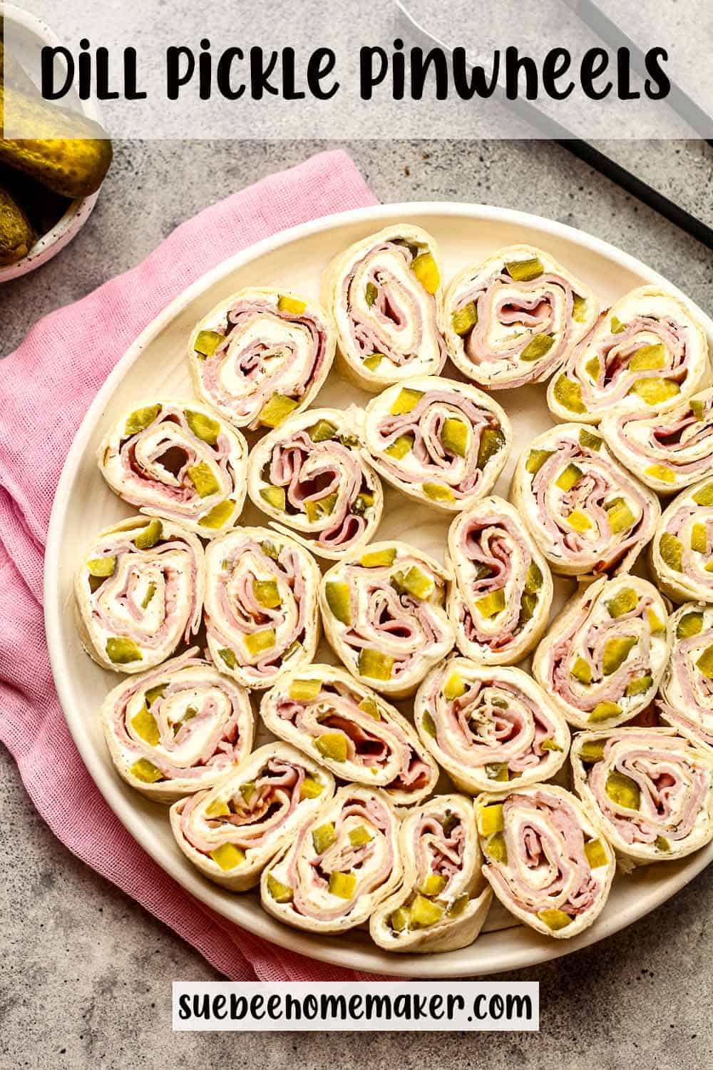 A plate of dill pickle pinwheels with a pink napkin.
