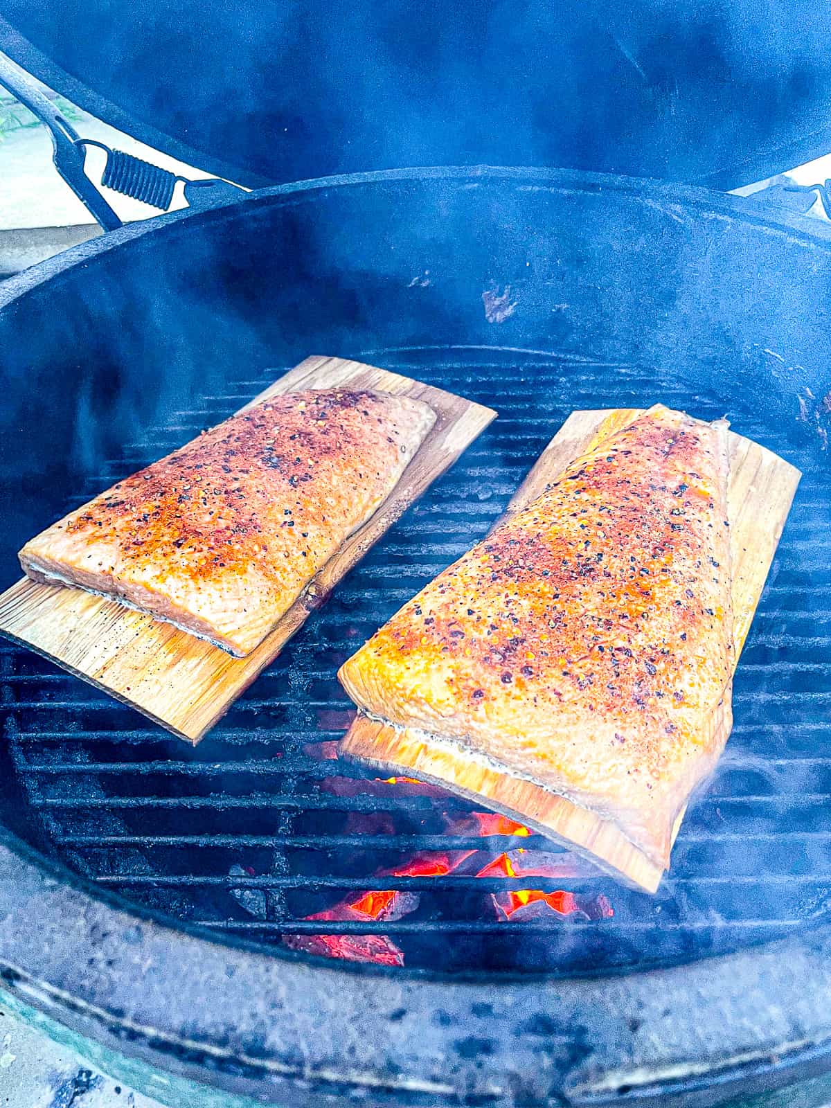 A grill with the cooked salmon on cedar planks.