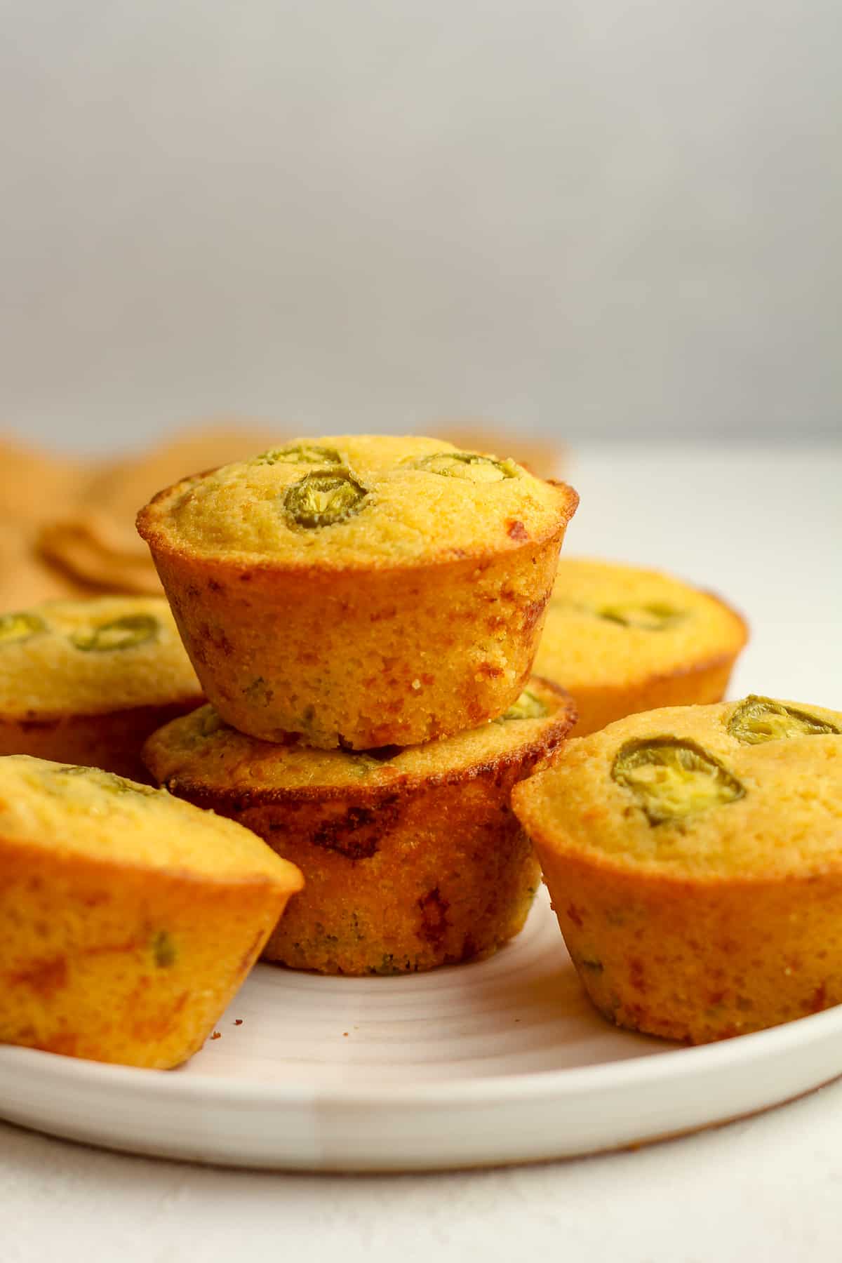 A plate of stacked jumbo cornbread muffins with jalapeno and cheese.
