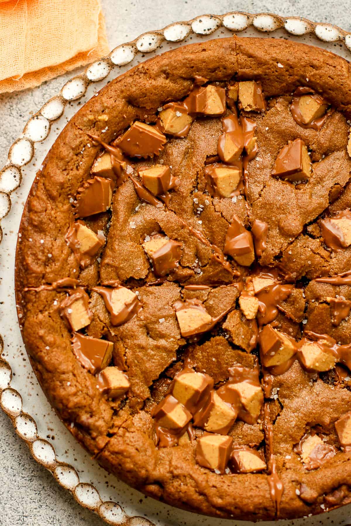 Closeup on a chocolate peanut butter cookie cake on a large plate.