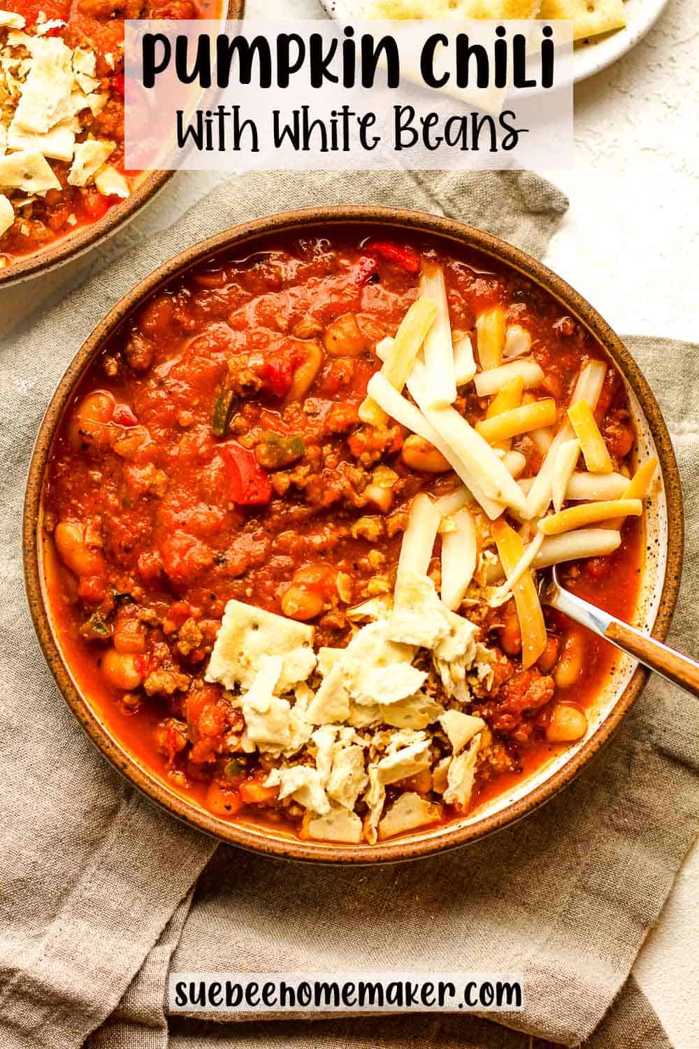 Closeup on a bowl of pumpkin chili with white beans and loaded with toppings.