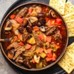 A bowl of beef soup with mushrooms.