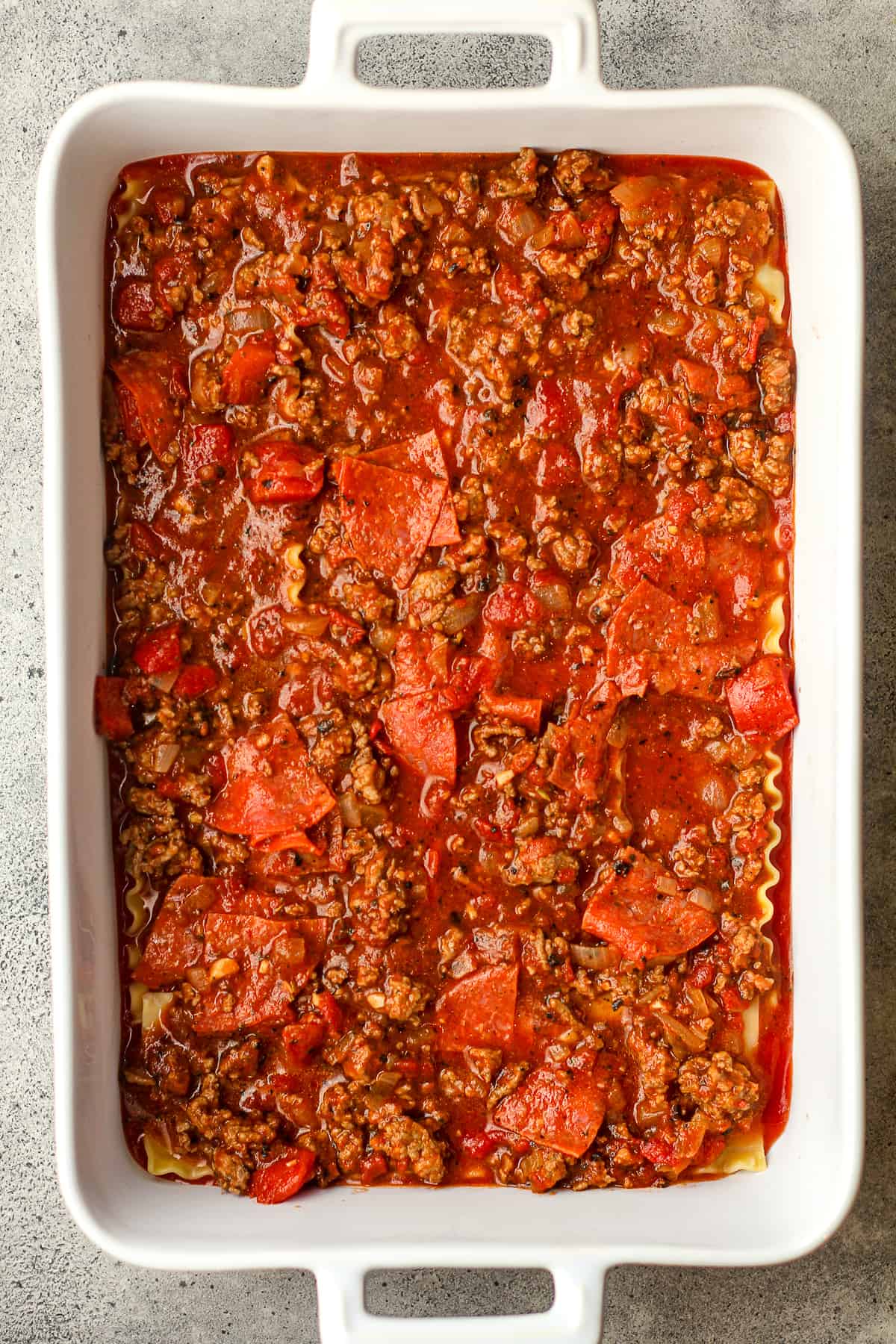 A casserole of lasagna with the meat layer on top.