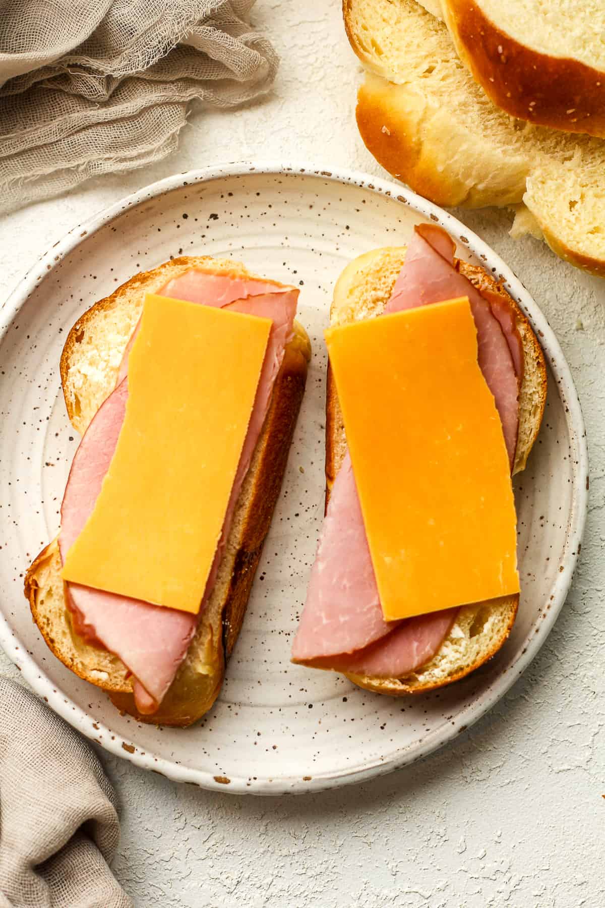 A plate of two slices of brioche with ham and cheese.