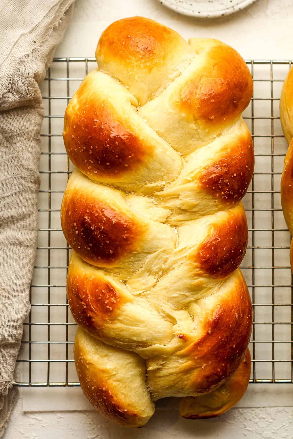 Closeup on a loaf of braided brioche bread on a wire rack.