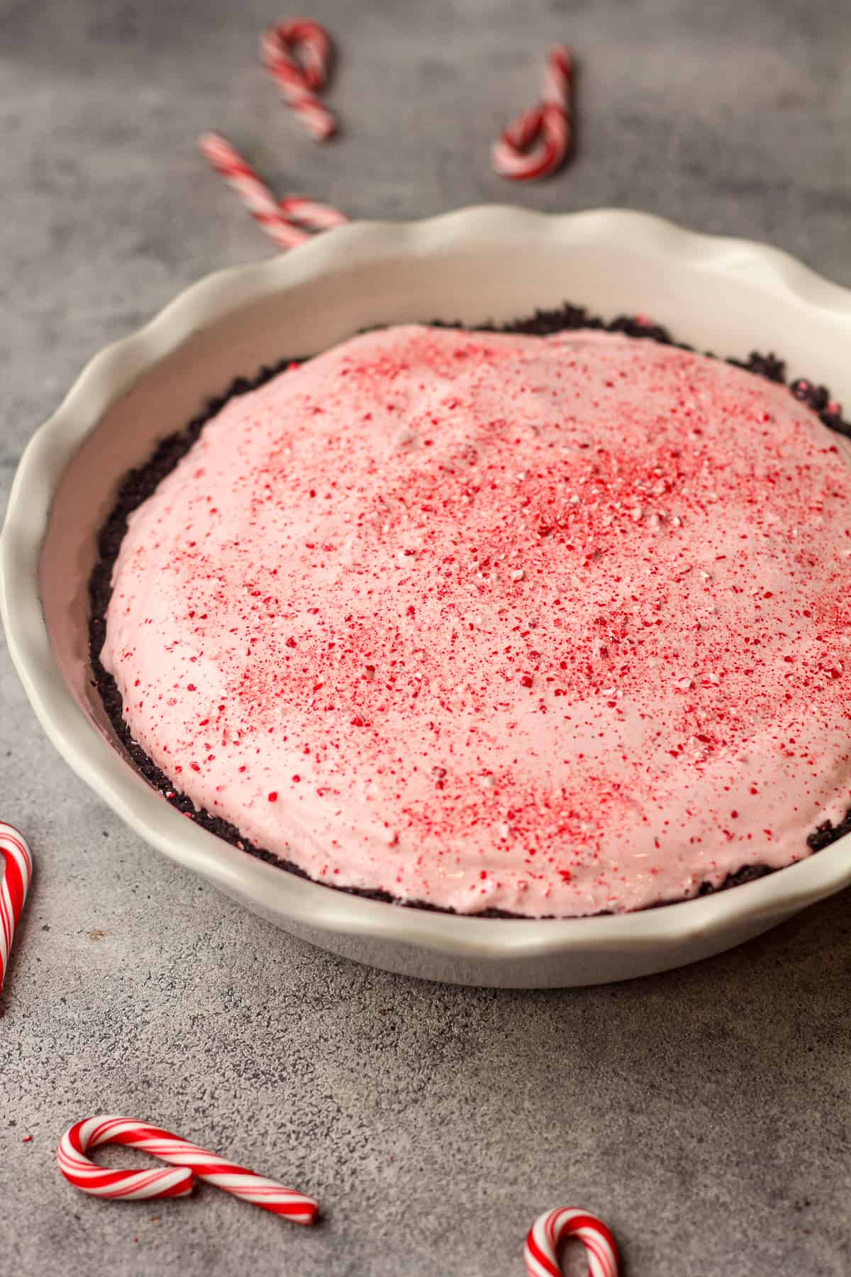 Side view of a candy cane pie with crushed peppermint on top.