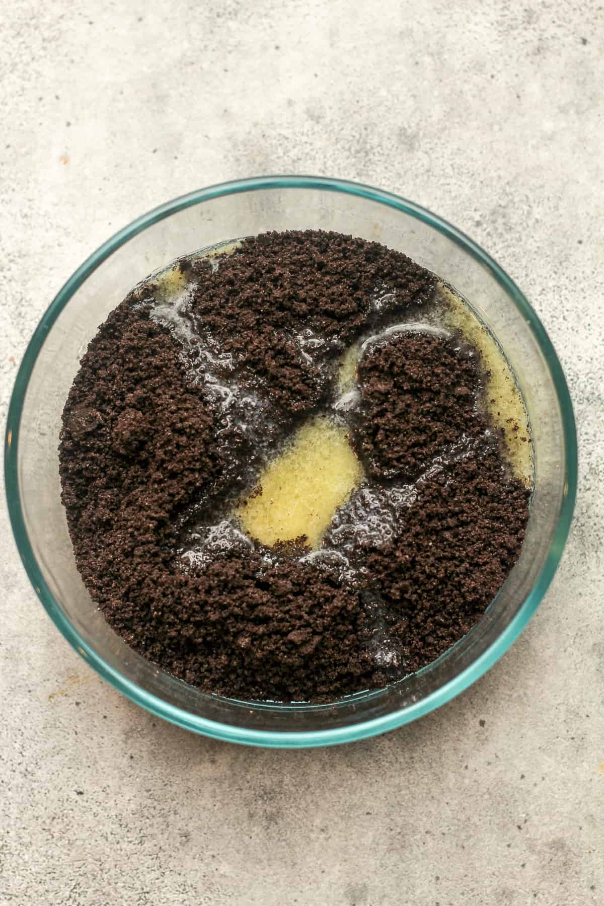A bowl of the crushed Oreos plus melted butter on top.