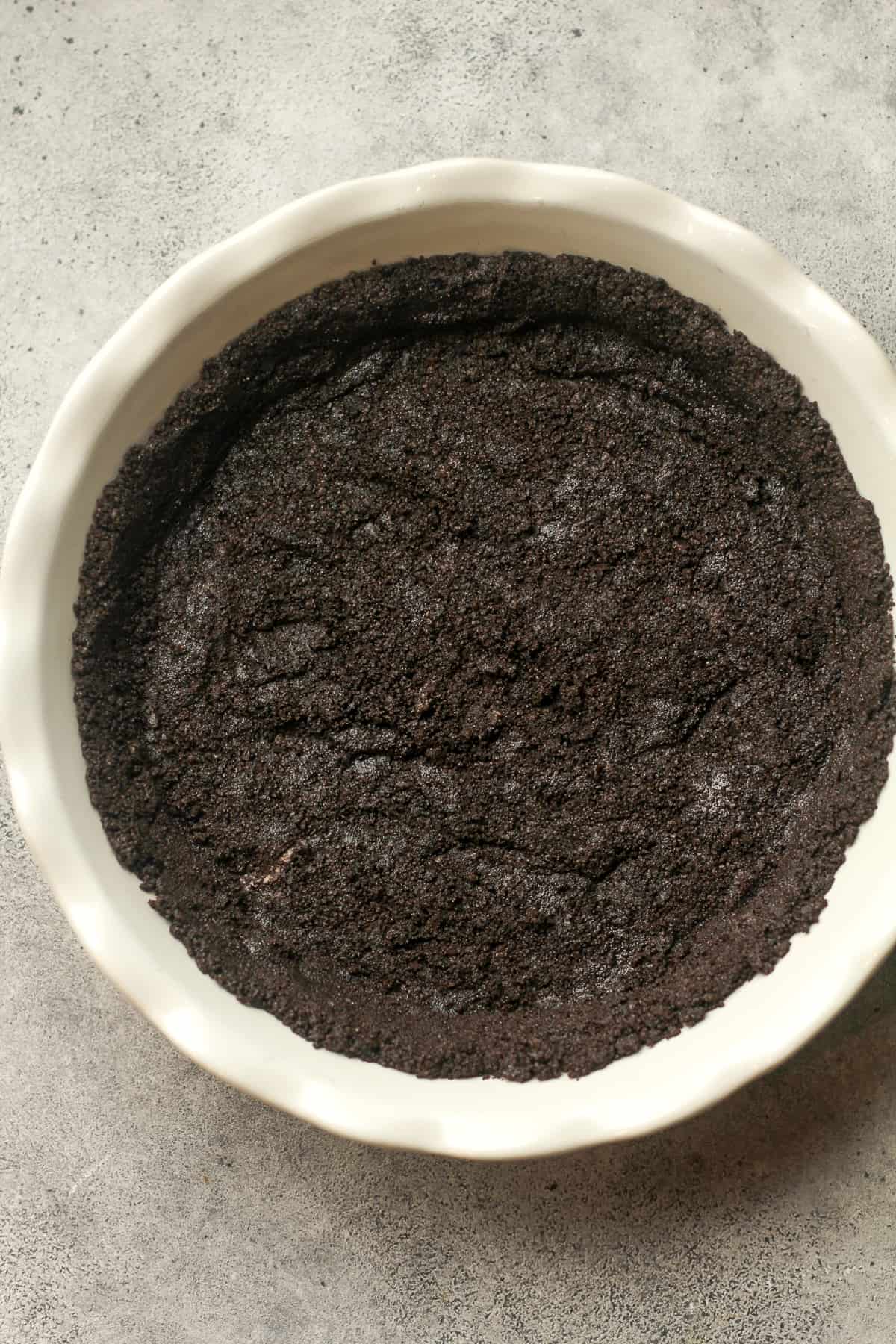 A pie dish with pressed Oreo crust inside.