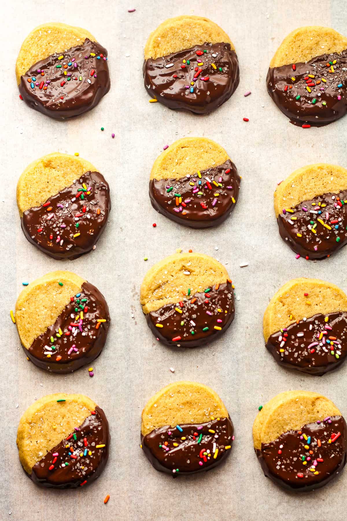 12 chocolate dipped shortbread cookies on white parchment paper.