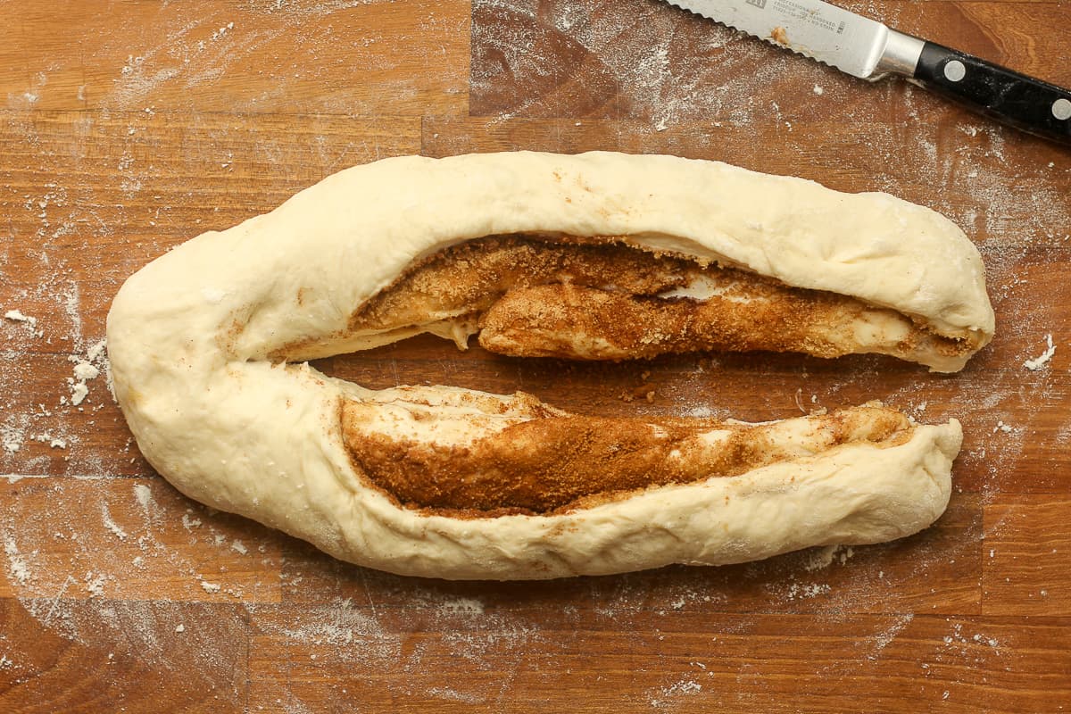A board with halved cinnamon bread dough.