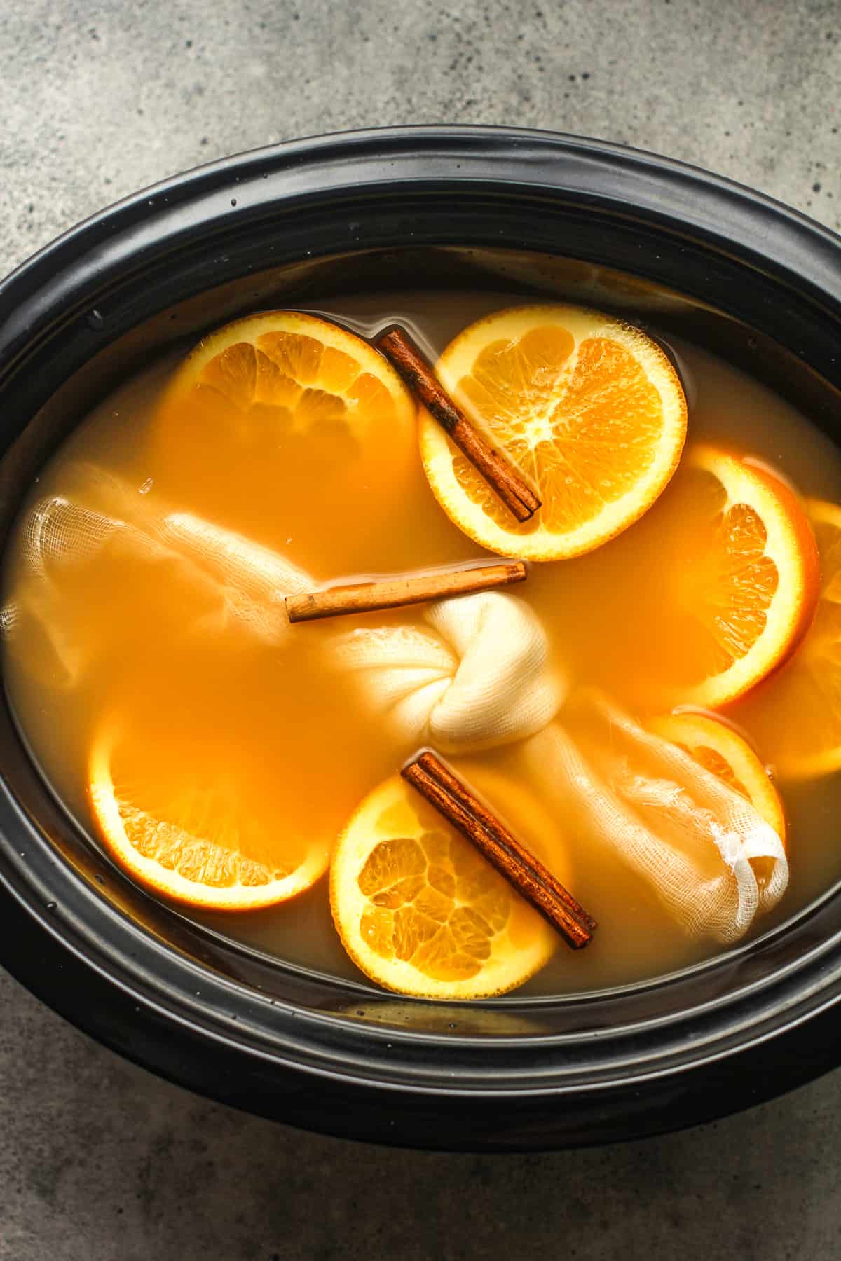 A crock pot of cider with orange slices etc.