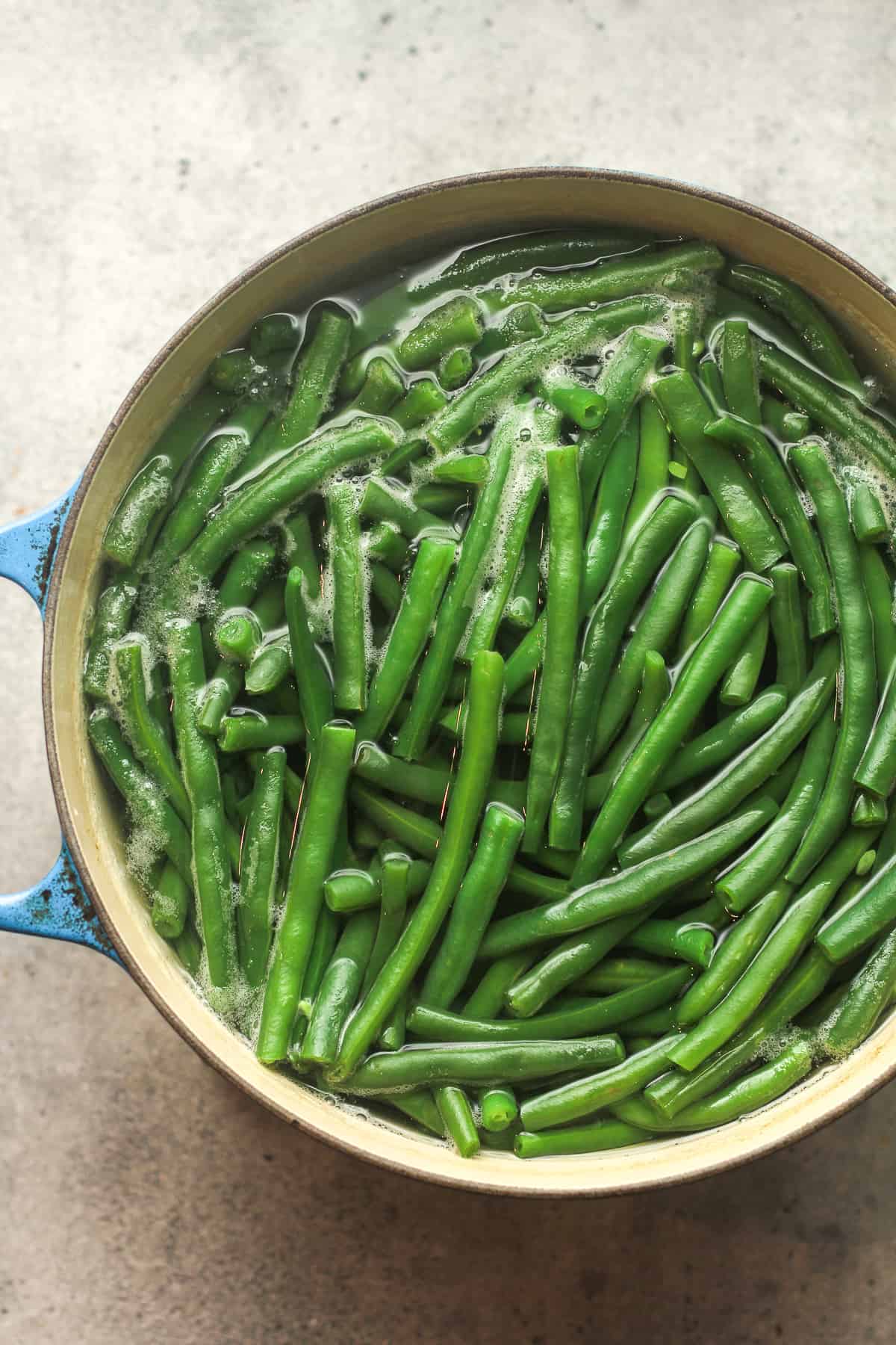 A pot of cooked green beans in water.