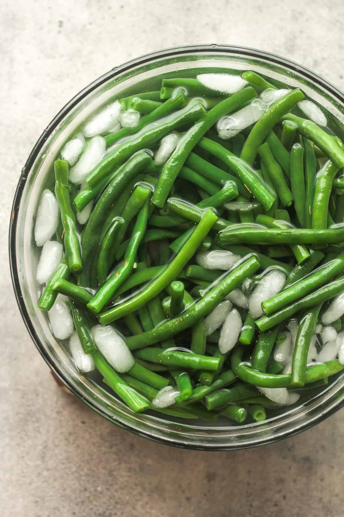 A large bowl of blanched green beans in an ice bath.