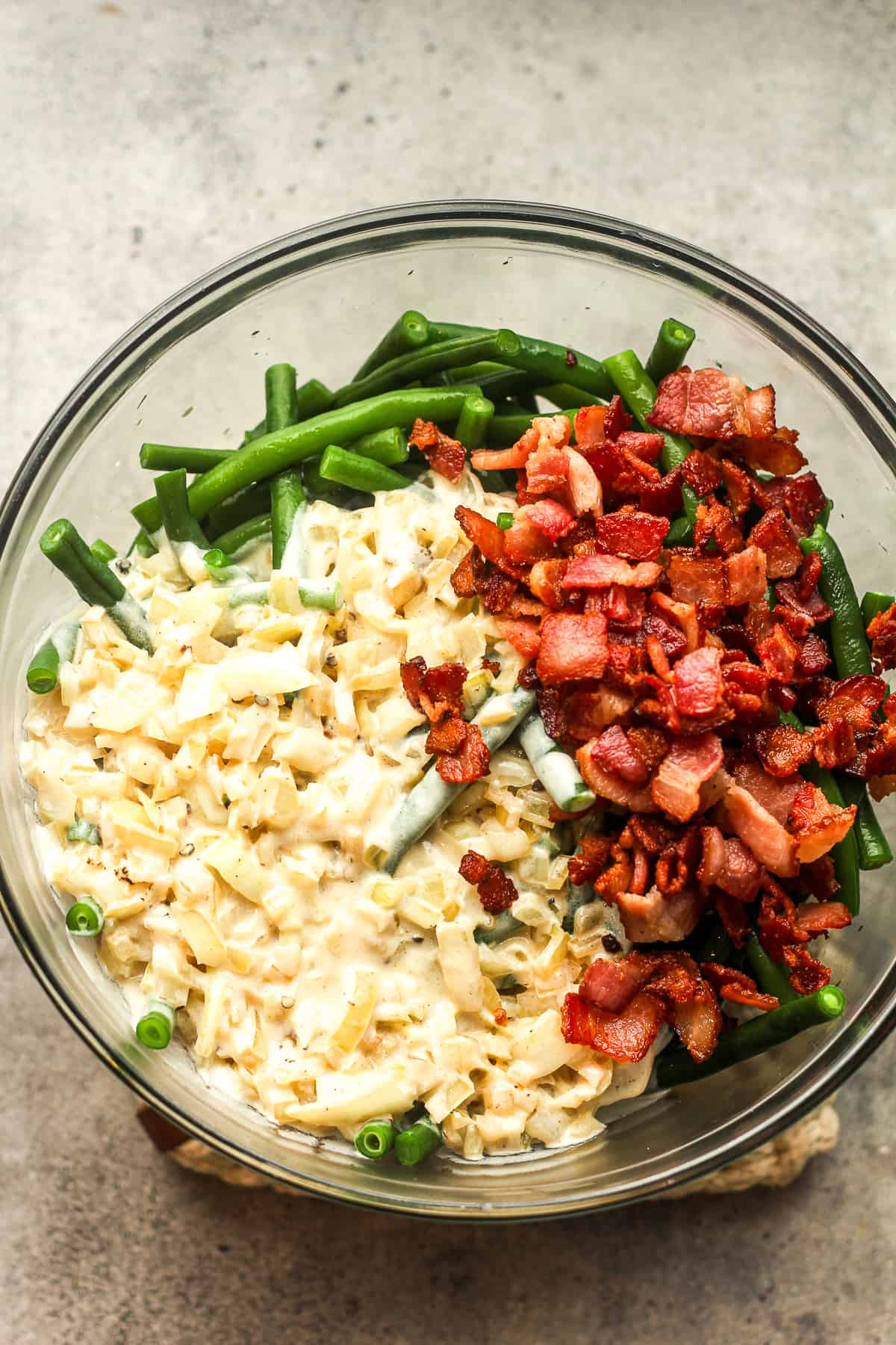 A bowl of the blanched green beans with the creamy roux and crispy bacon on top.