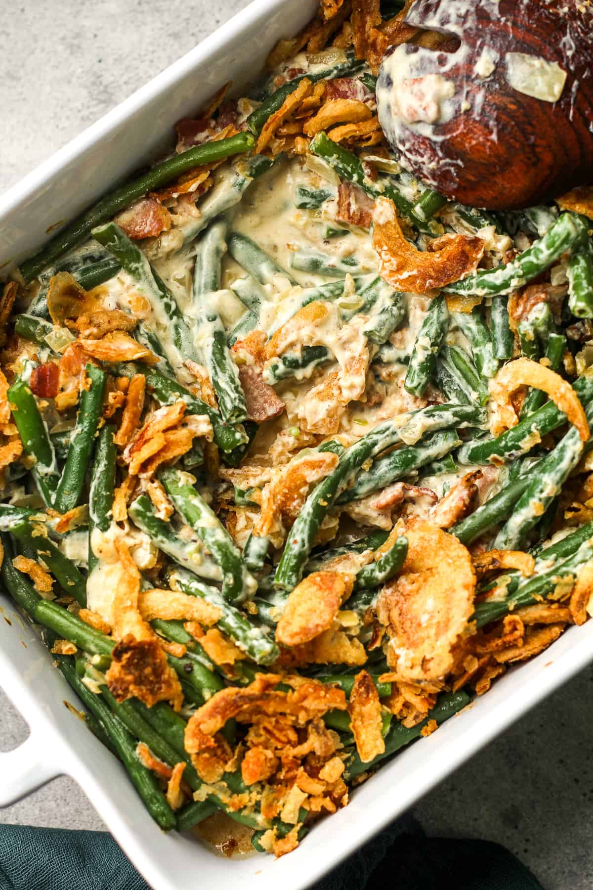 Closeup view of a casserole dish with green bean casserole with a spoonful removed.