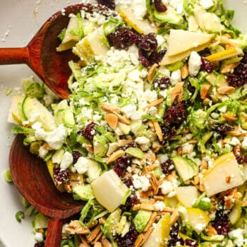 Closeup on shaved Brussels sprouts salad with pears, dried cherries, goat cheese, and slivered almonds.