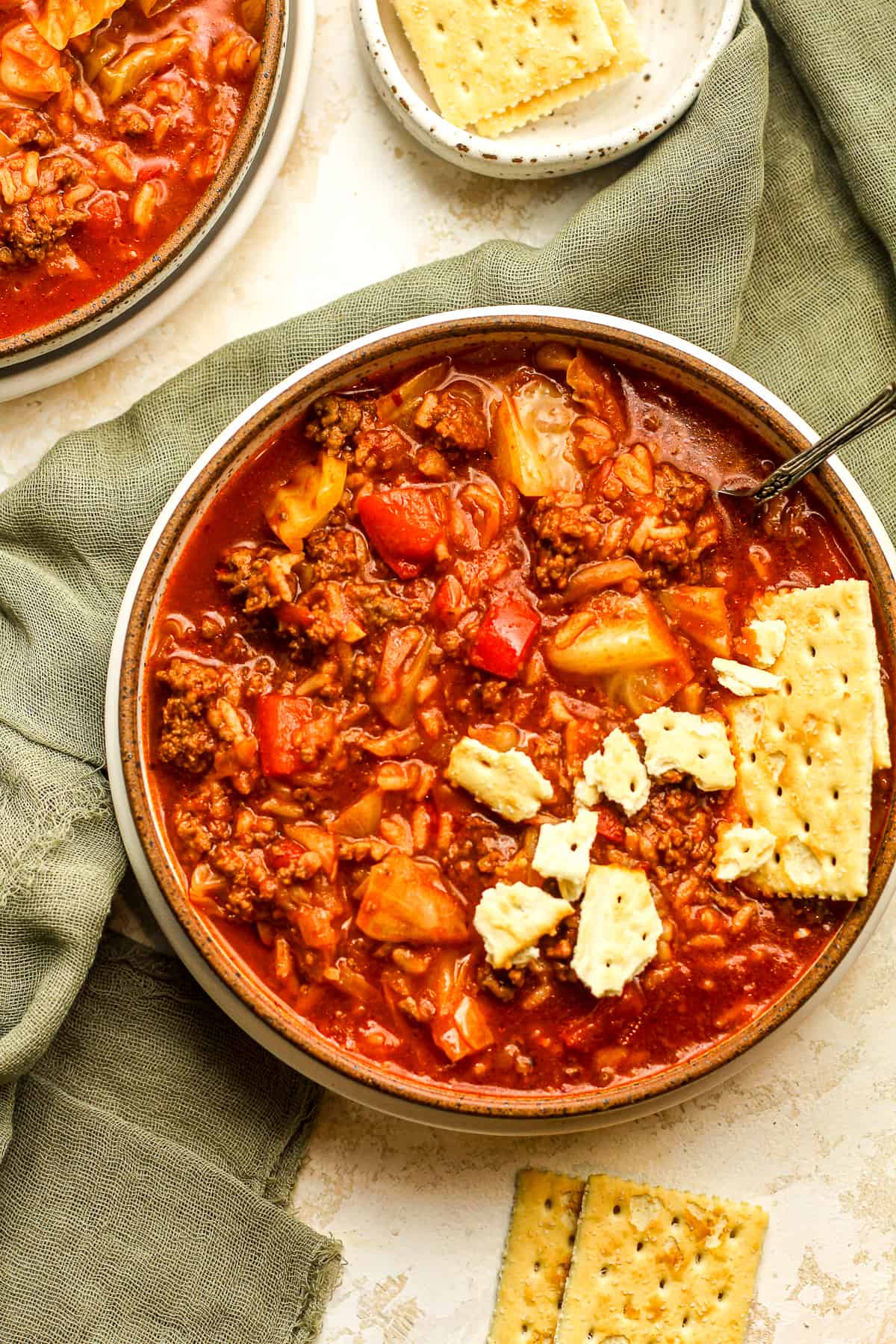 A bowl of stuffed cabbage soup with saltine crackers.