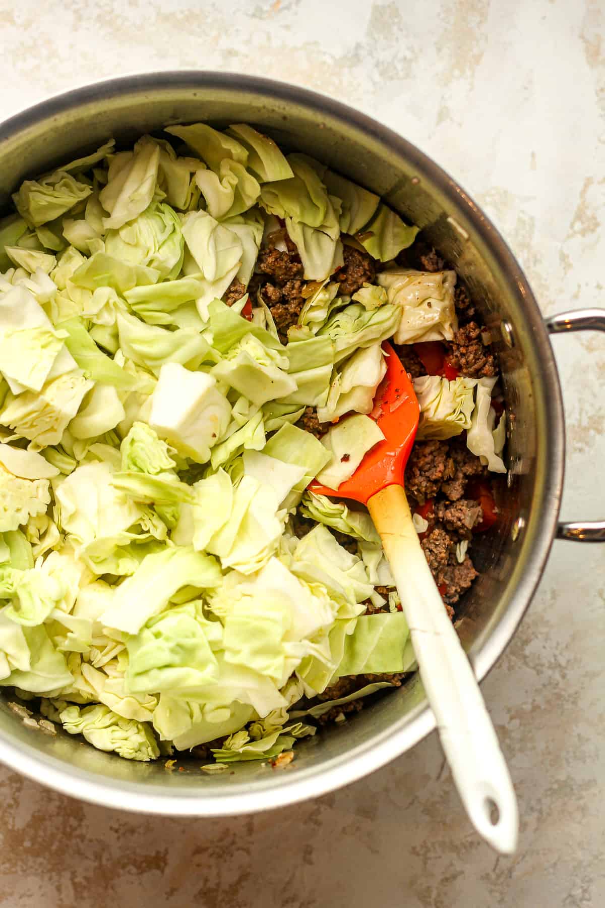 A pot of the browned beef with chopped cabbage on top.