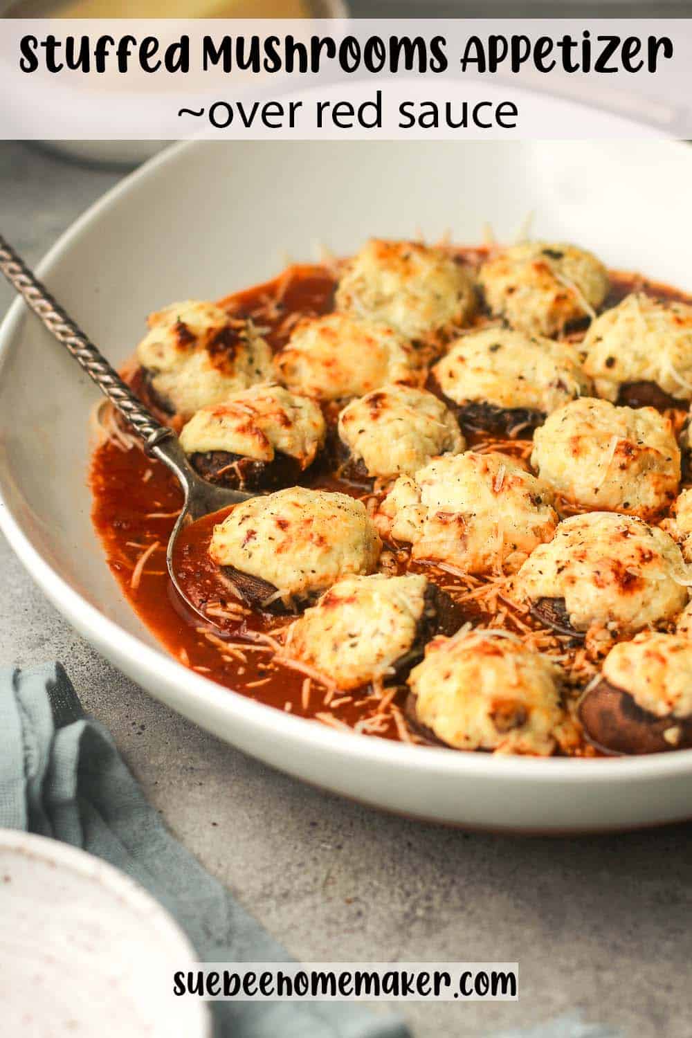 A side view of a platter of stuffed mushrooms over red sauce.