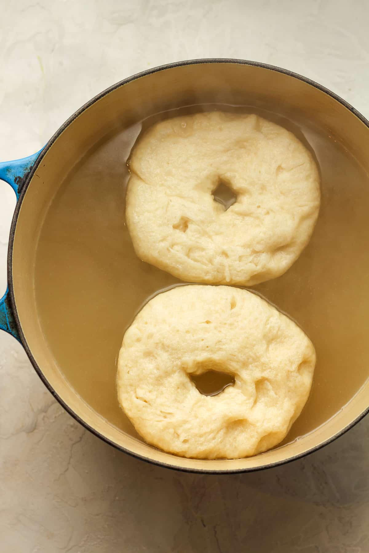 Two bagels in a boiling pot of water.