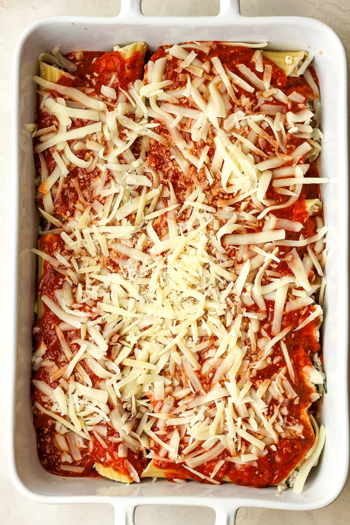 A large casserole dish of beef and cheese manicotti before baking.