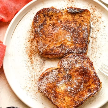 A plate of brioche French toast with cinnamon and powdered sugar.