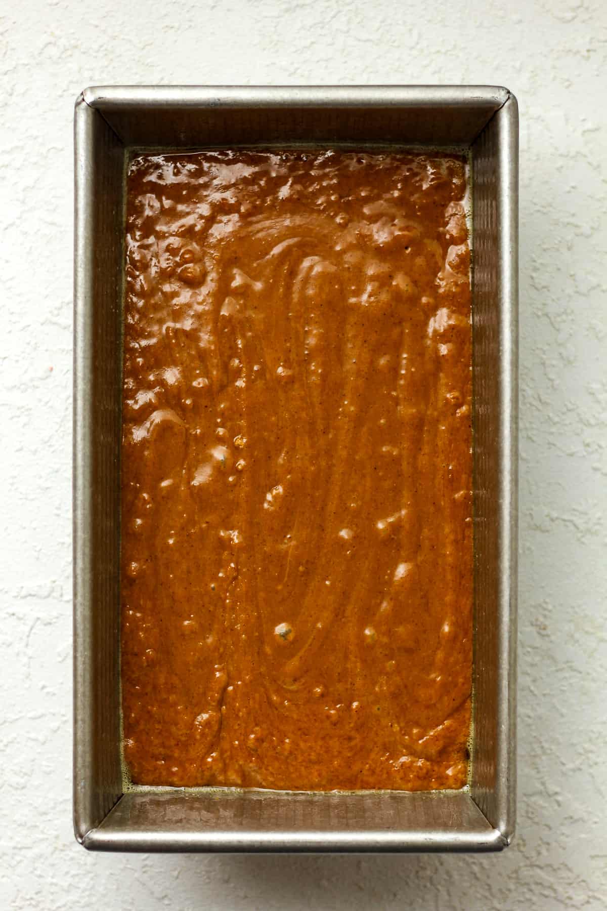 A large loaf pan filled with gingerbread batter.