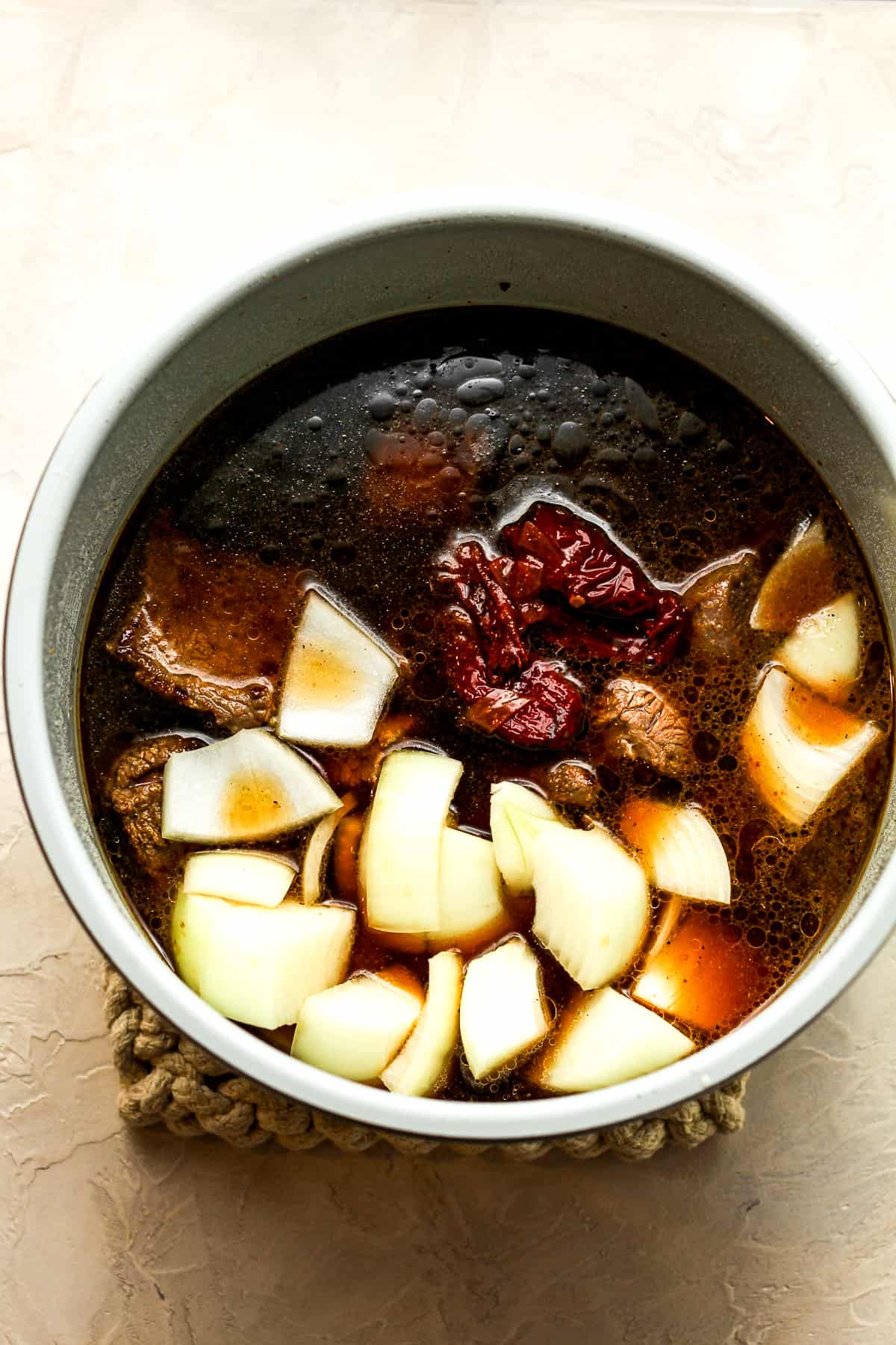 A bowl of an instant pot with the browned beef plus additions.