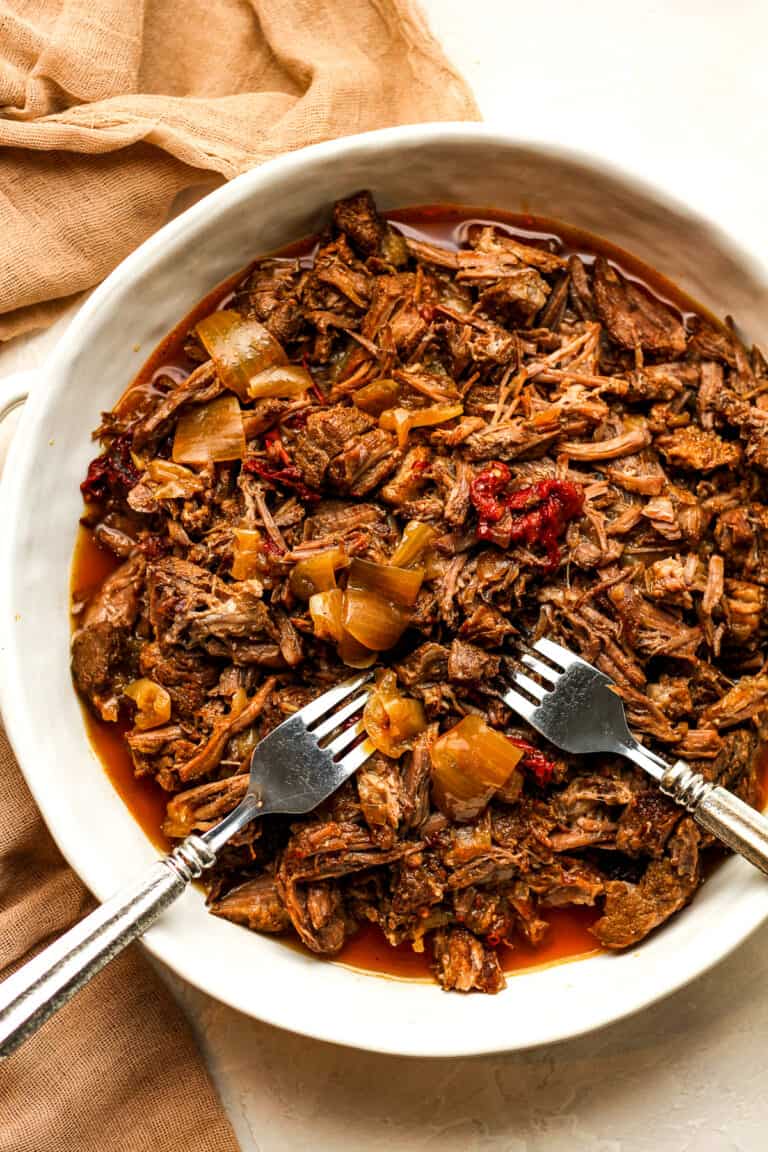 A bowl of shredded beef with two forks.
