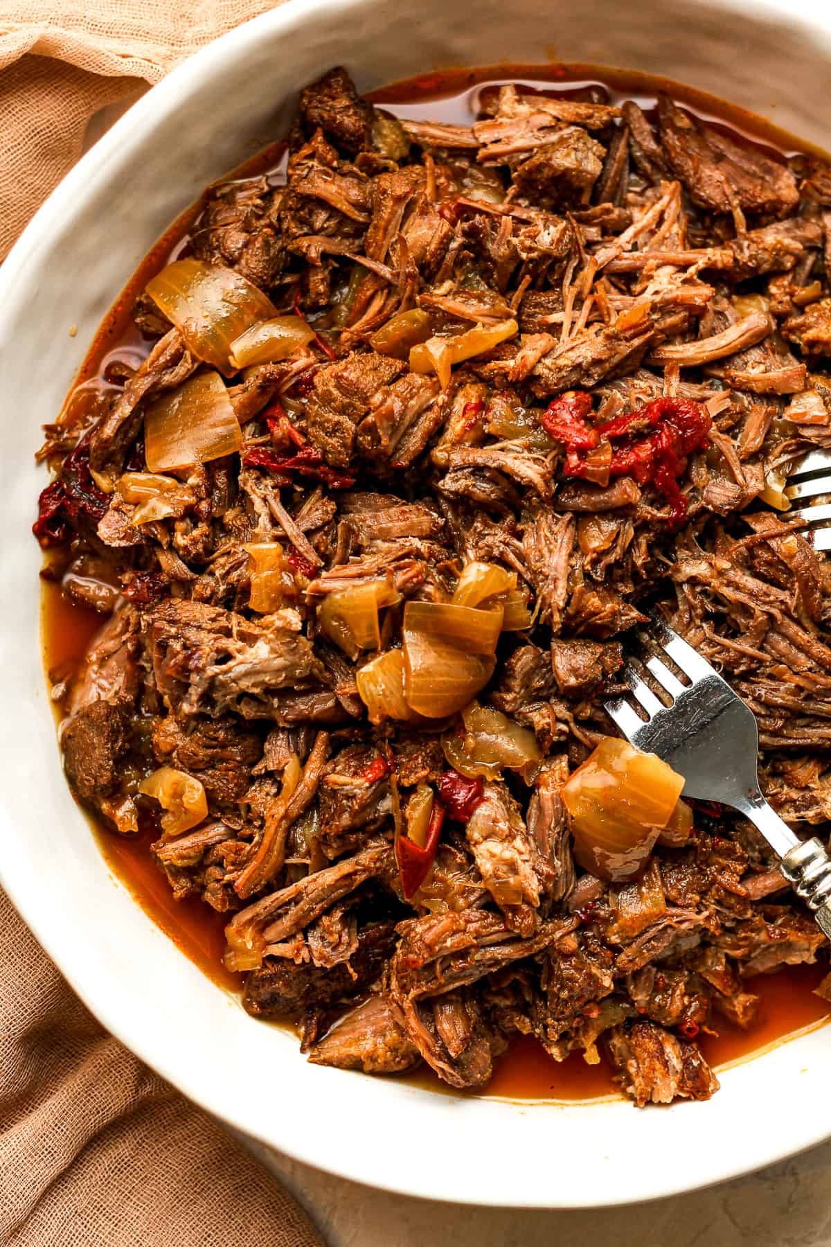 A bowl of instant pot shredded beef with onions.