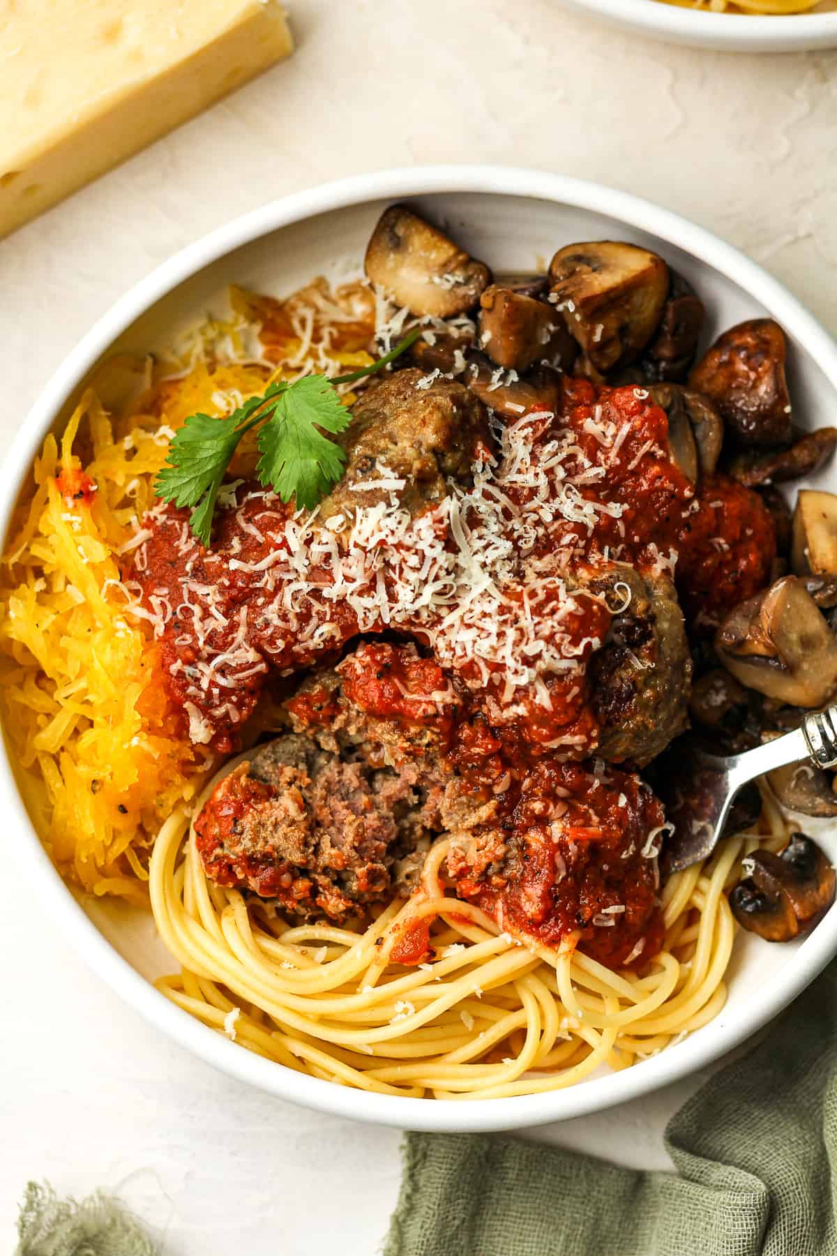 Overhead view of a bowl of meatballs with marinara and a bite out of a meatball.