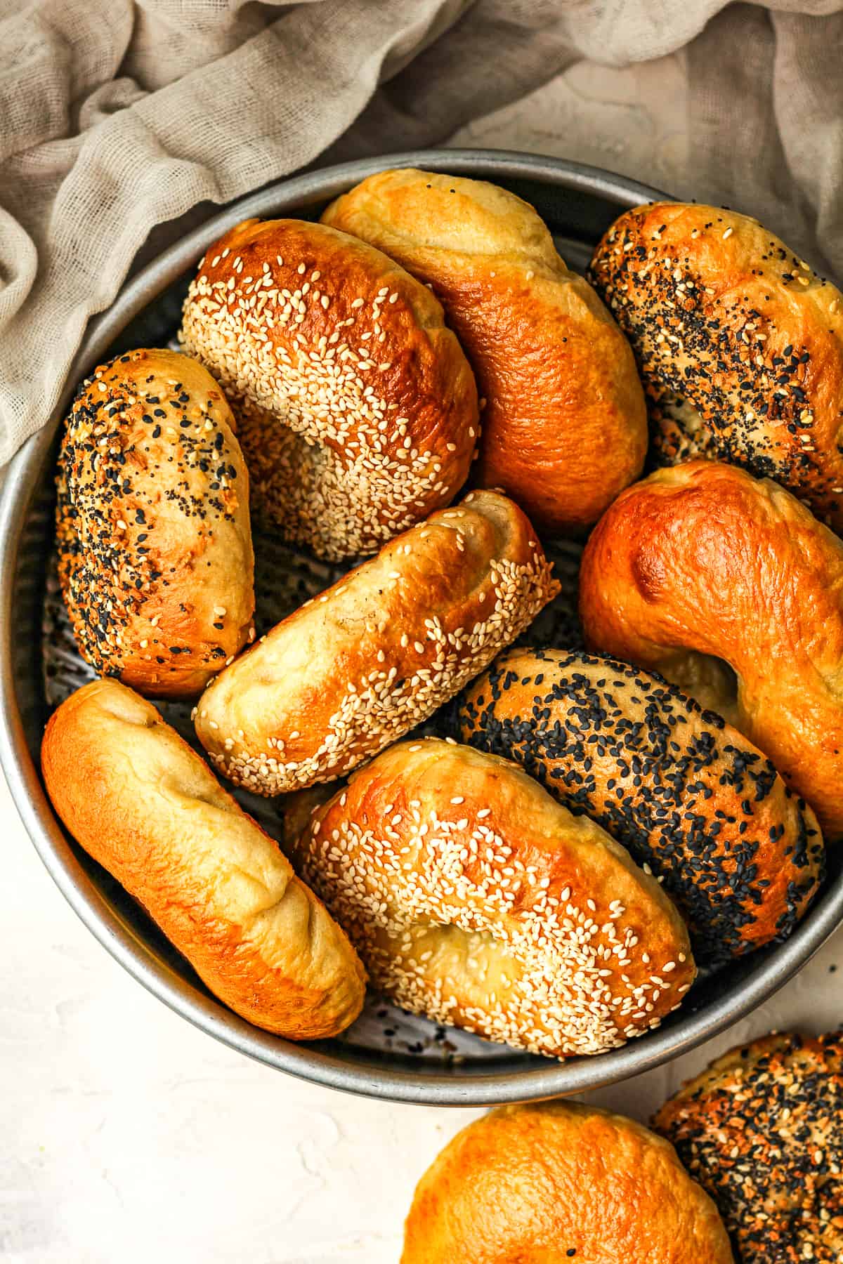 A round pan with bagels stacked sideways.