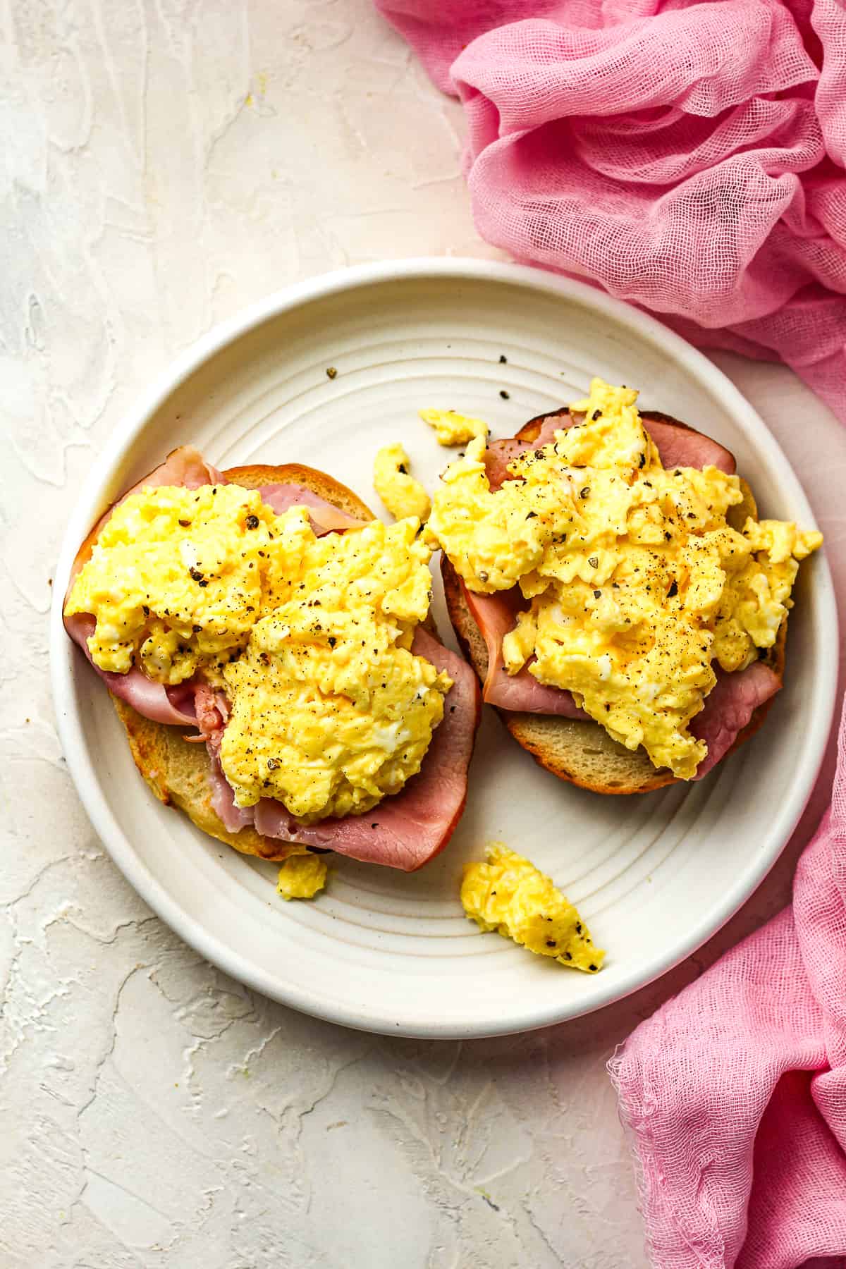 A bagel toasted and topped with ham and eggs.