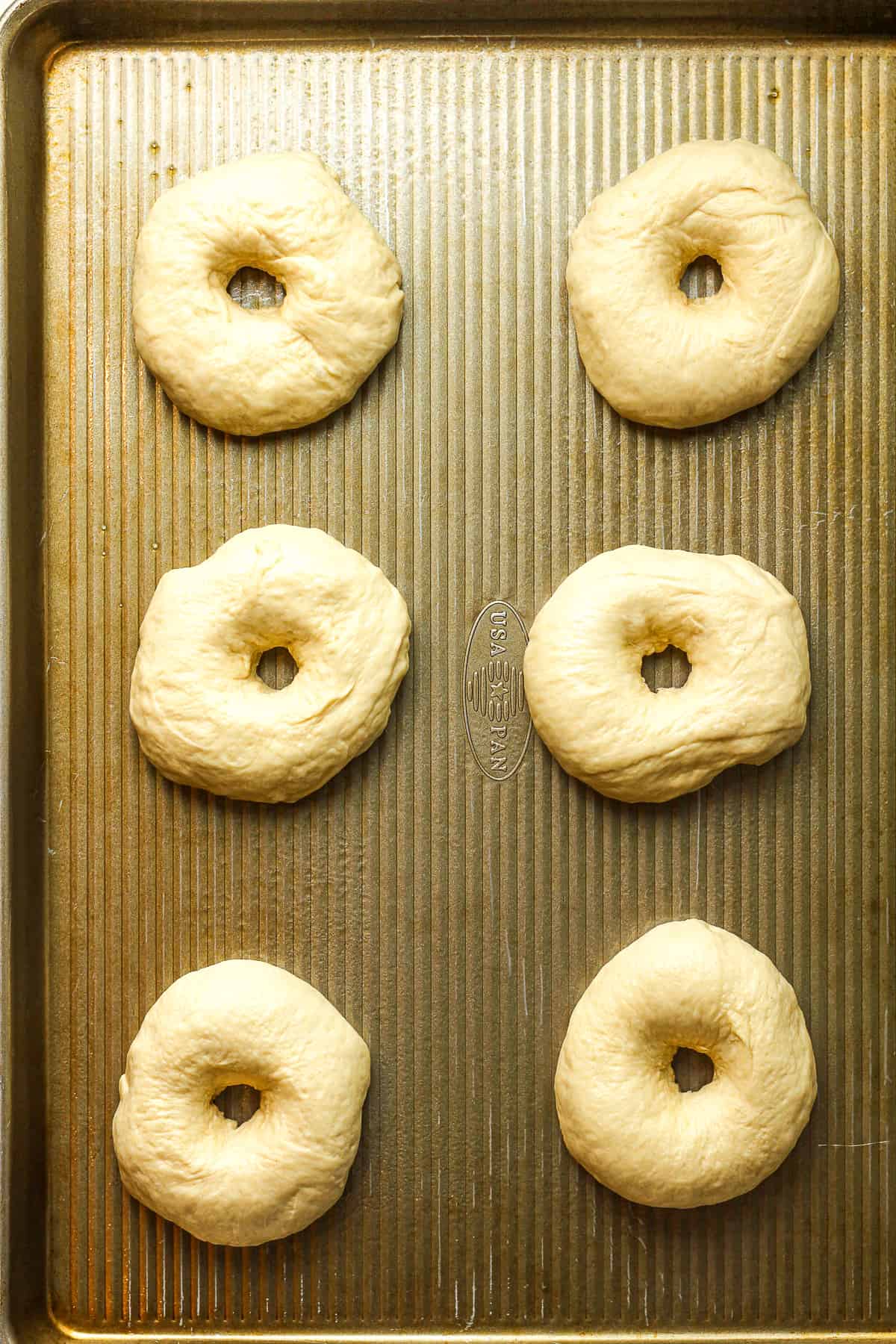 A baking sheet with the bagel shapes.