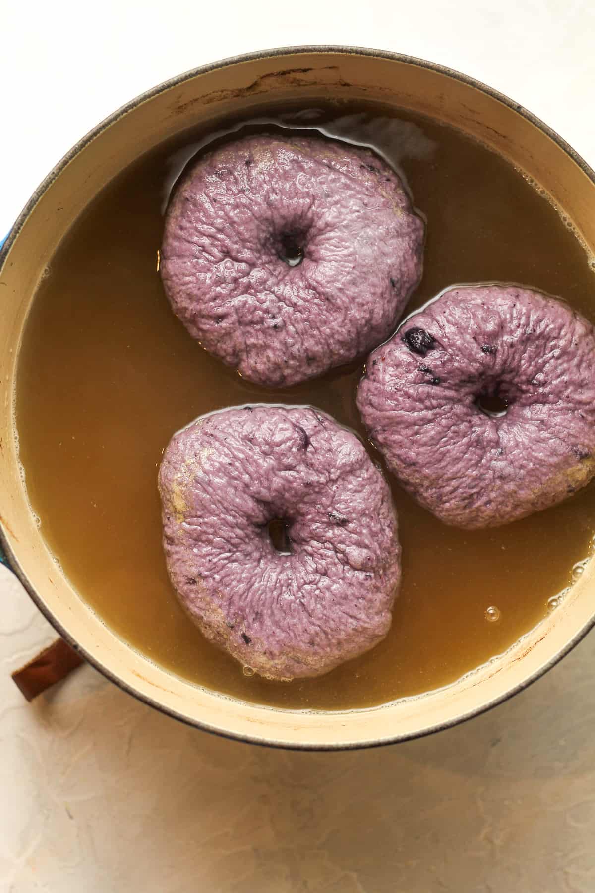 A stock pot of bagels in boiling water.