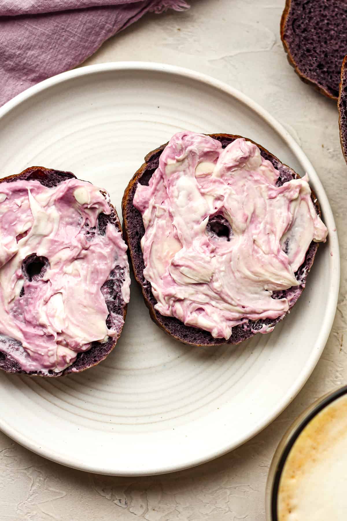 Closeup on a blueberry bagel on a plate with cream cheese.