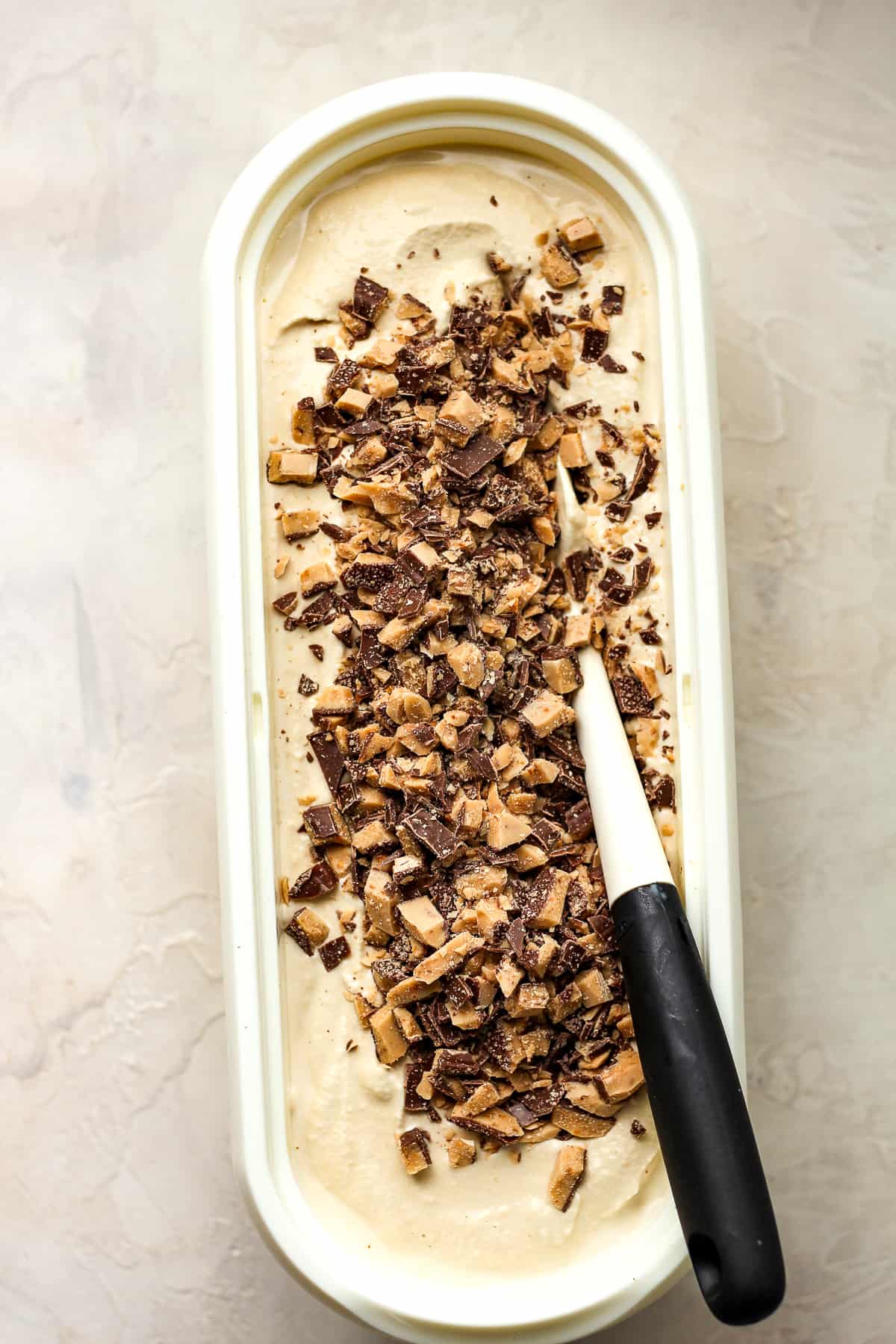 A container of the coffee ice cream with chopped toffee on top.